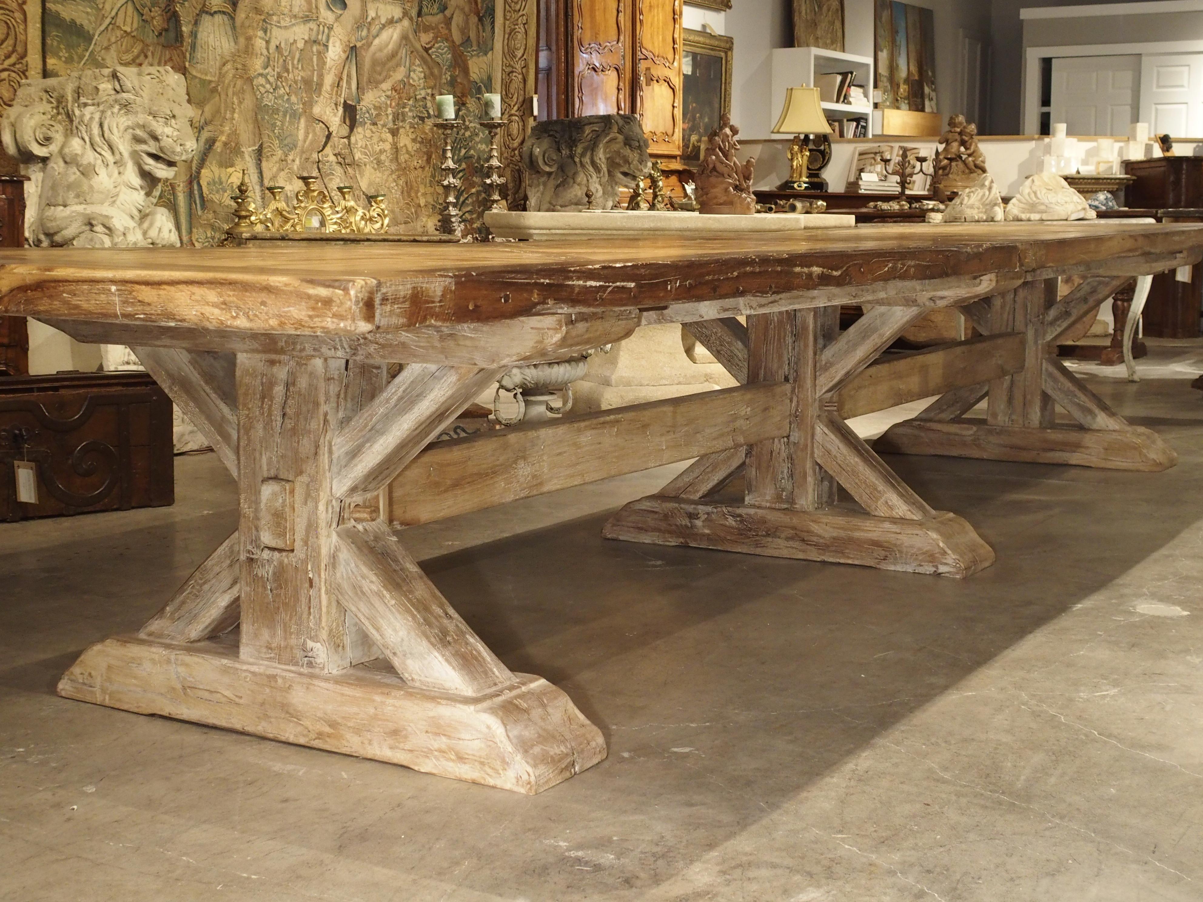 This impressive French dining table is made of thick oak boards and has a parquet inset top. The top has been made with planks that vary in coloration and grain, while the thicker frame around the parquet is in a slightly darker stain. The base of
