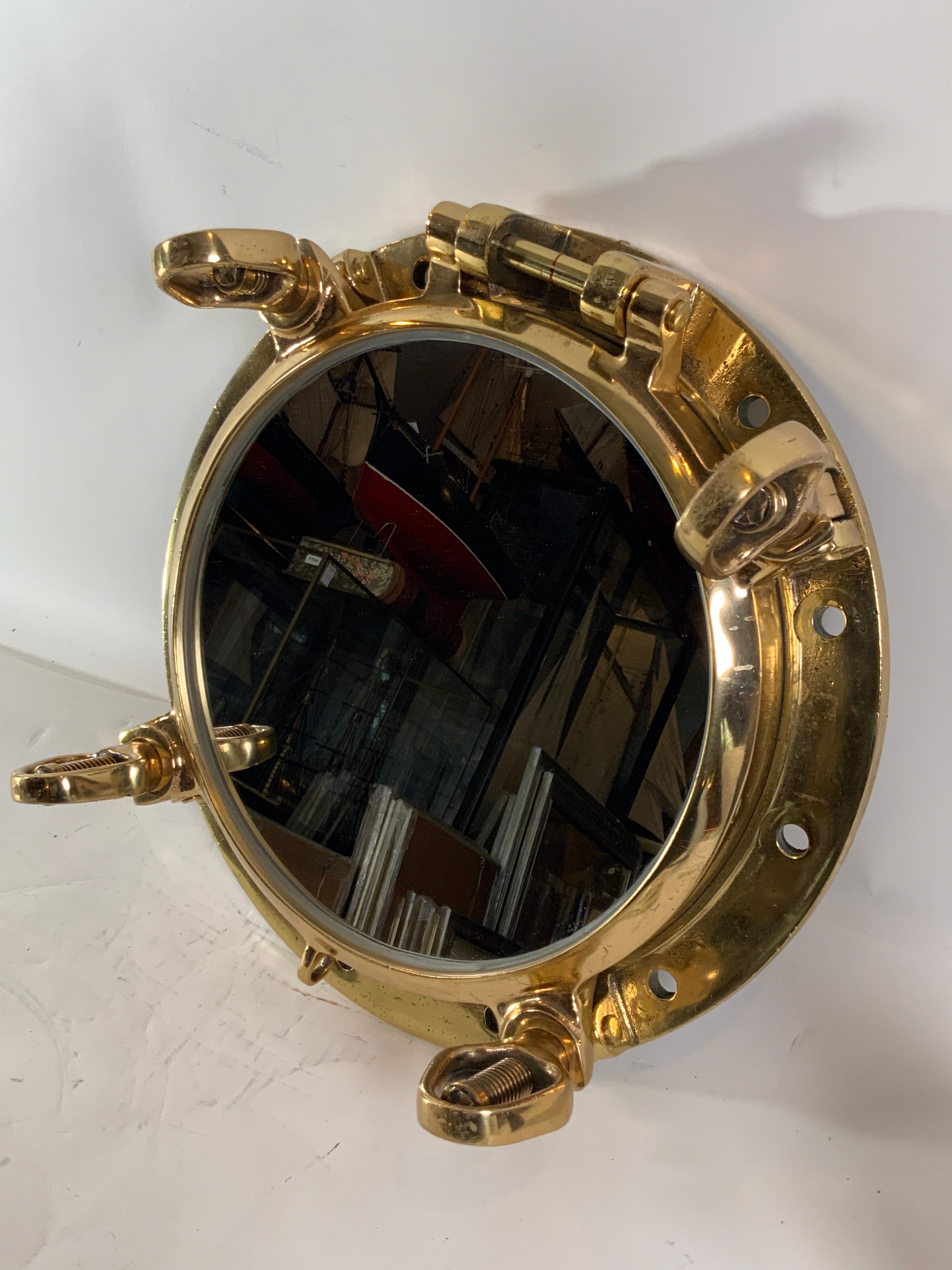 Highly polished authentic ship's porthole. Fitted with a glass mirror. Hinged port with four 