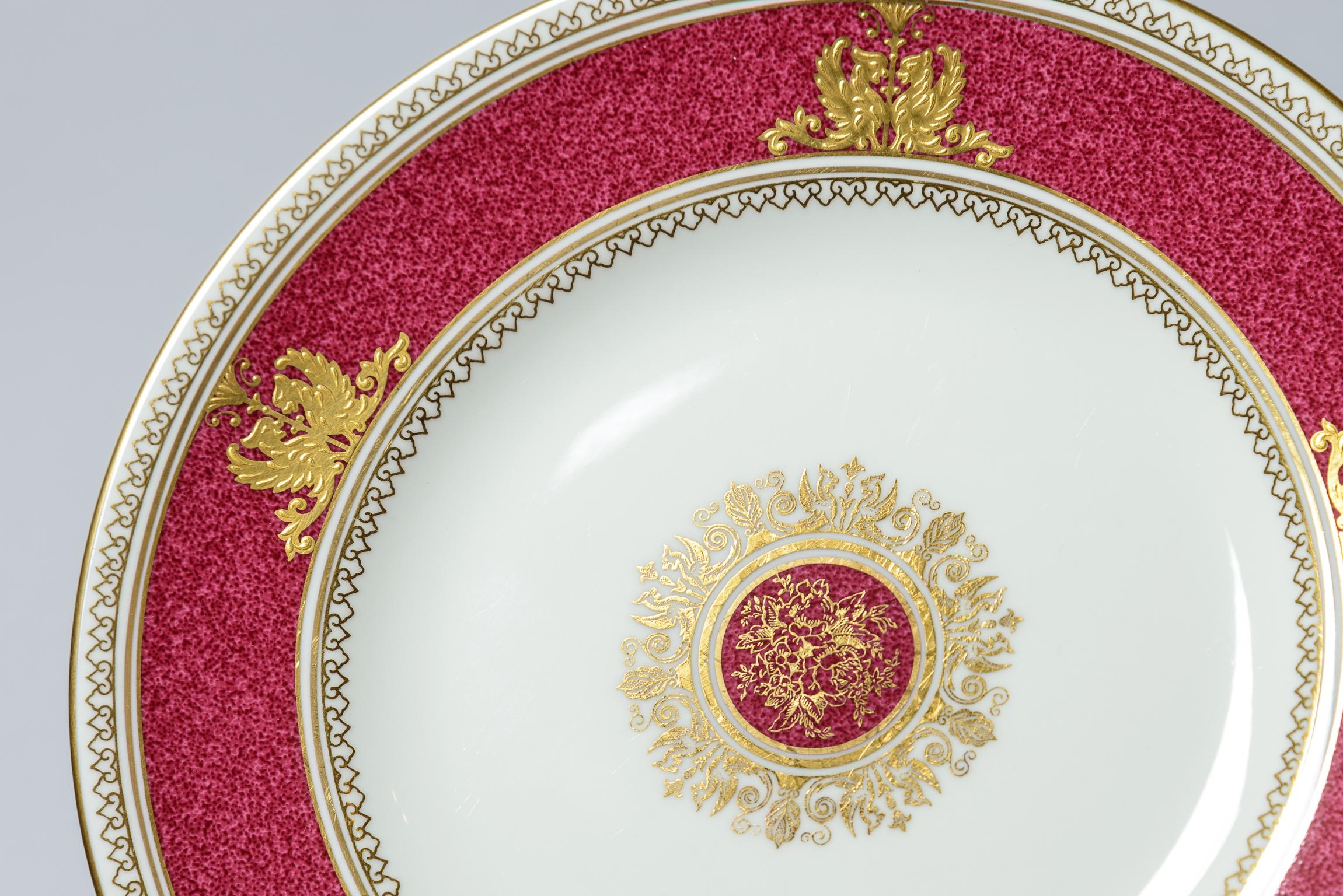A pretty set of 16 plates with a ruby powder finished collar accented with a raised double griffin gilt motif and central floral medallion. Classic and elegant and on Wedgwood's crisp white bone porcelain. The eight inch size is very flexible and