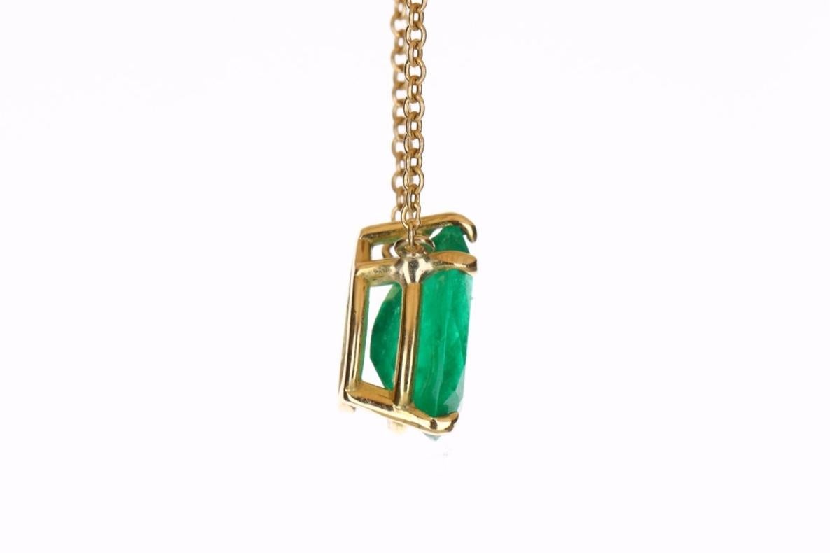 Displayed is a classic Colombian emerald solitaire necklace set in 18K yellow gold. This gorgeous solitaire piece carries a natural emerald in a five-prong setting. Fully faceted, this gemstone showcases excellent shine. The emerald has very good