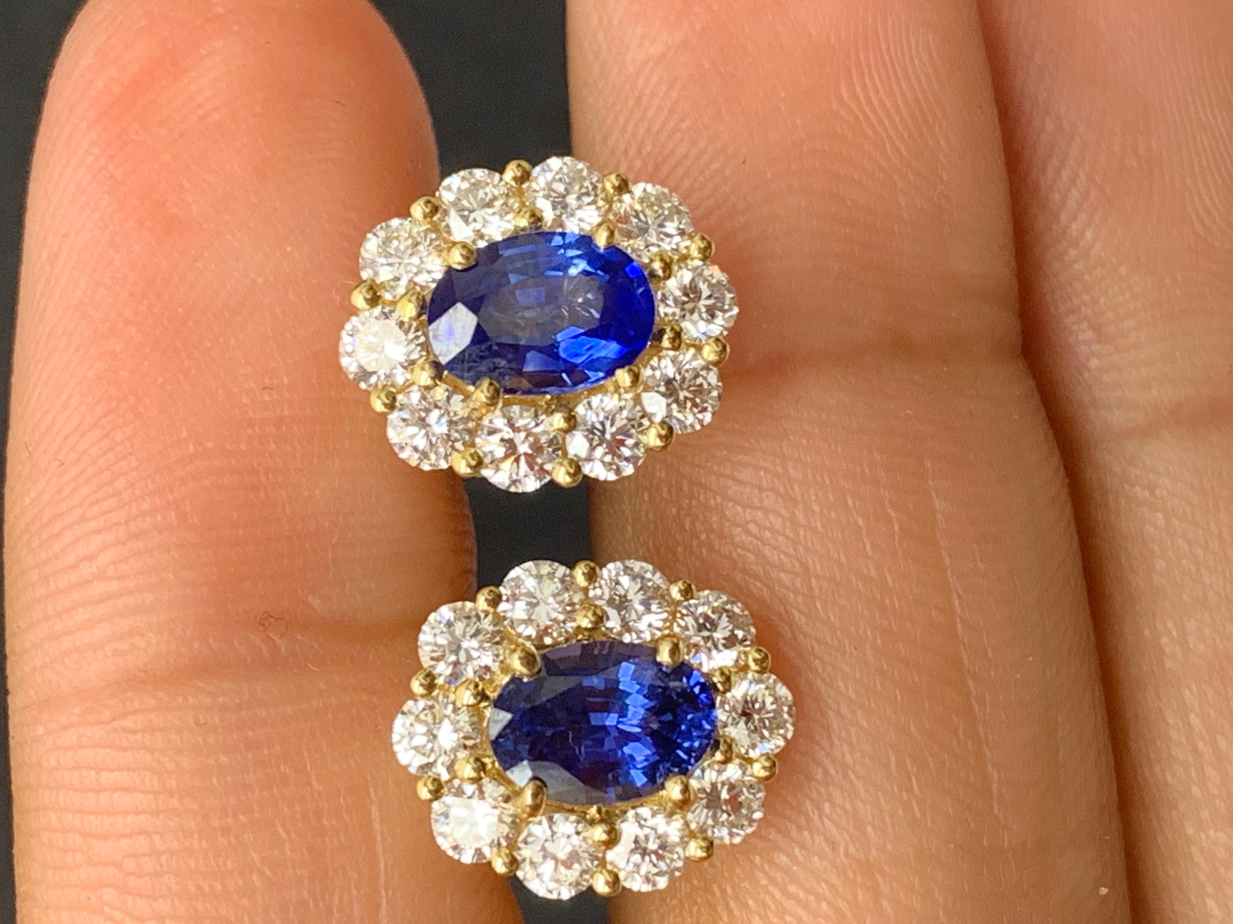 A simple pair of stud earrings showcasing 1.60 carats of 2 oval cut lush blue sapphires, surrounded by a single row of 20 round brilliant diamonds weighing 1.35 carats. Made in 18-karat white gold.