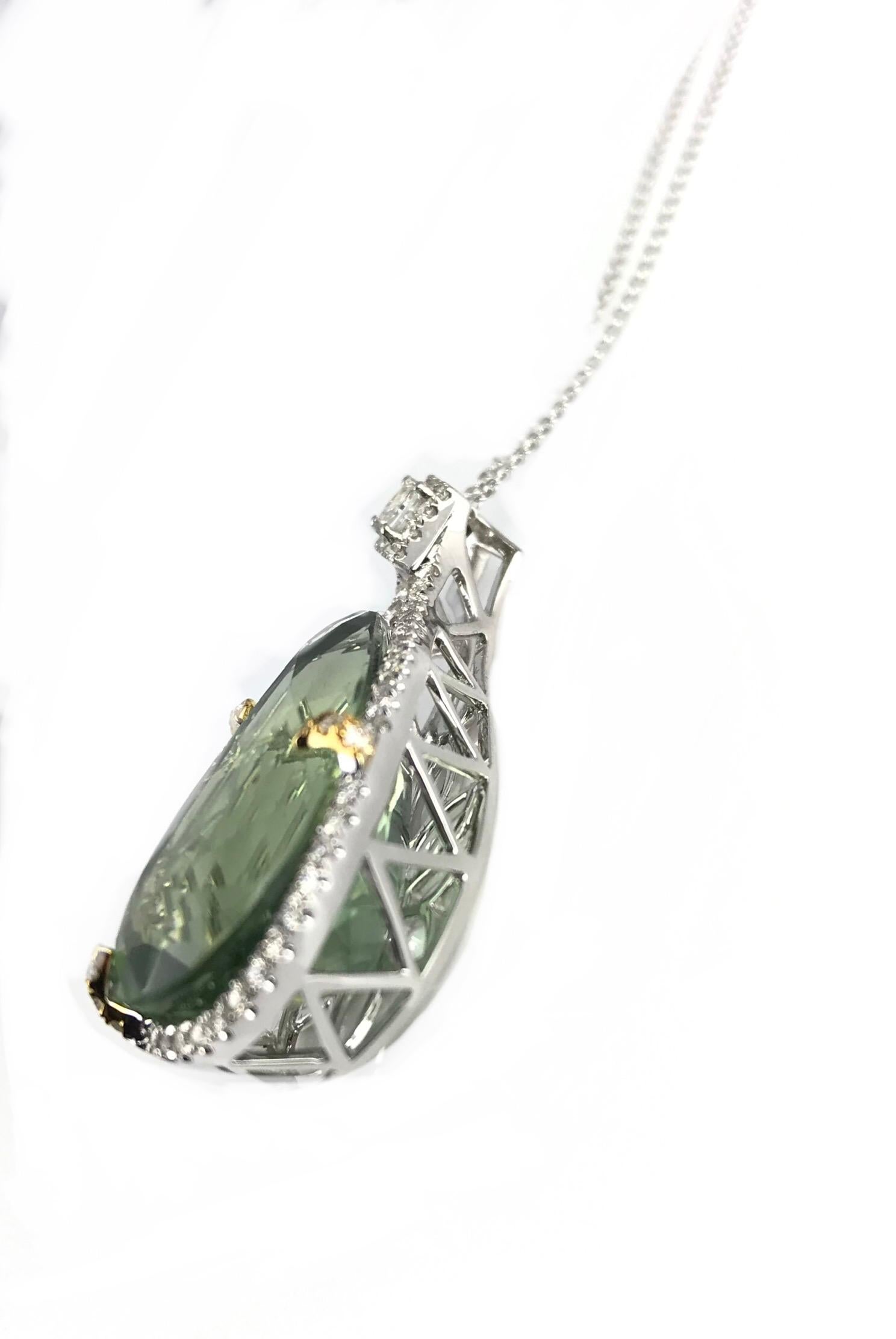 (DiamondTown) This stunning pendant has a 16.06 carat pear shaped exotic kiwi green amethyst, tucked inside a border of round white diamonds. One princess cut diamond, also in a halo of smaller diamonds, decorates the bail. Total diamond weight 0.53