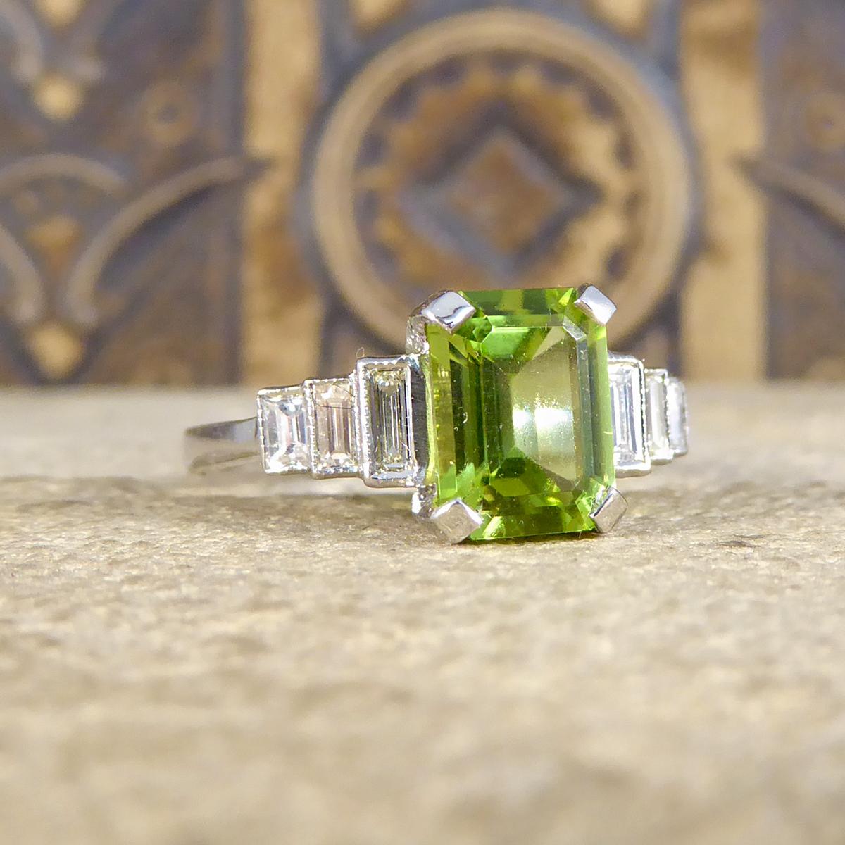 Dieser atemberaubende Ring verfügt über einen Peridot im Smaragdschliff in einer Eckfassung mit vier Klauen und einem Gewicht von 1::60 ct. Es wurde fast so gestaltet:: dass es einem Art-Deco-Stück ähnelt:: mit drei Diamanten im Baguetteschliff auf