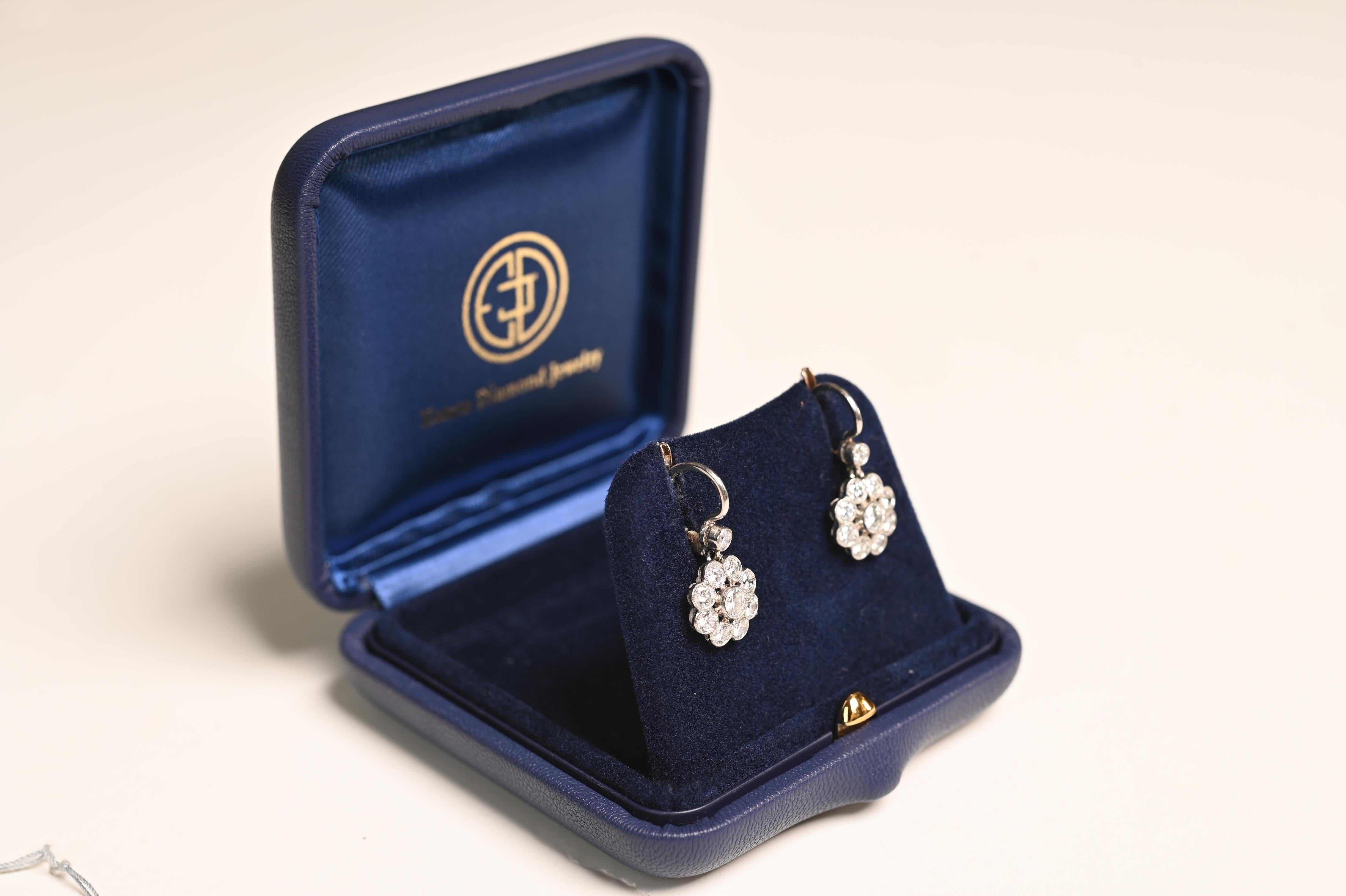 A stunning pair of floral motif diamond earrings, exquisitely crafted to showcase timeless elegance. Each earring features a delicate cluster of brilliant round-cut diamonds, meticulously bezel-set and adorned with intricate milgrain detailing. The