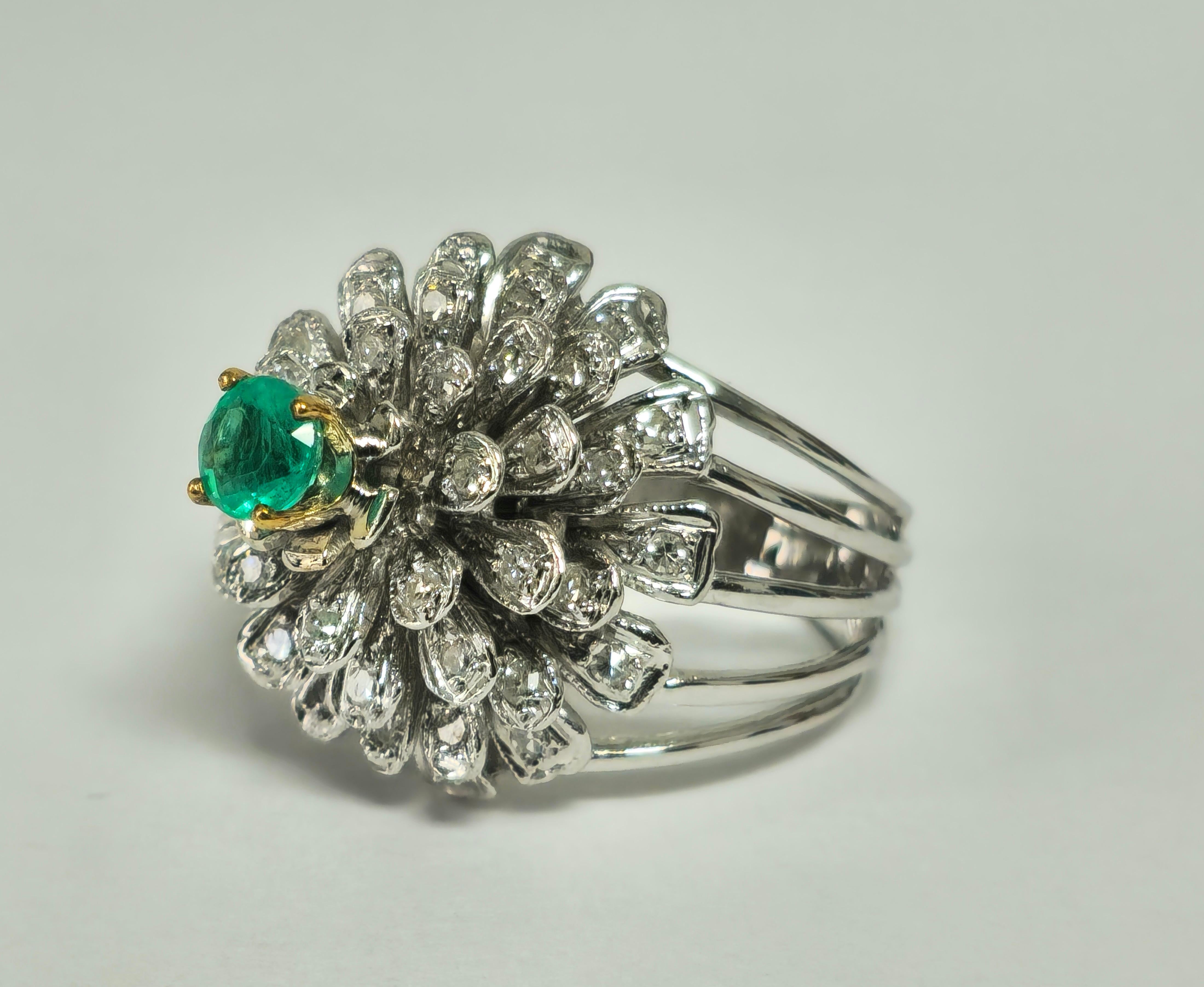 Sein Herzstück ist ein faszinierender kolumbianischer Smaragd, der Wachstum und Wohlstand symbolisiert. Er ist umgeben von einem Halo aus seitlichen Diamanten, die alle eine tadellose Reinheit und Farbe aufweisen. Das exquisite Blumen- und