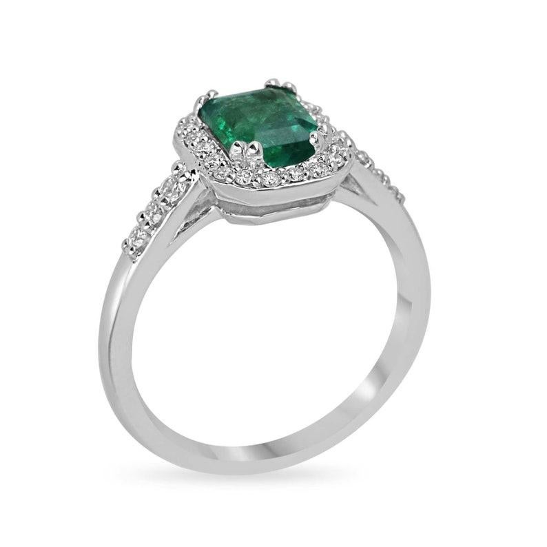 Elevate your proposal with our exquisite Emerald and Diamond Halo Engagement Ring. Nestled at its heart is a stunning 1.30-carat Zambian emerald, exuding a lush, rich green hue that's as captivating as the origin itself. Meticulously crafted in 14k