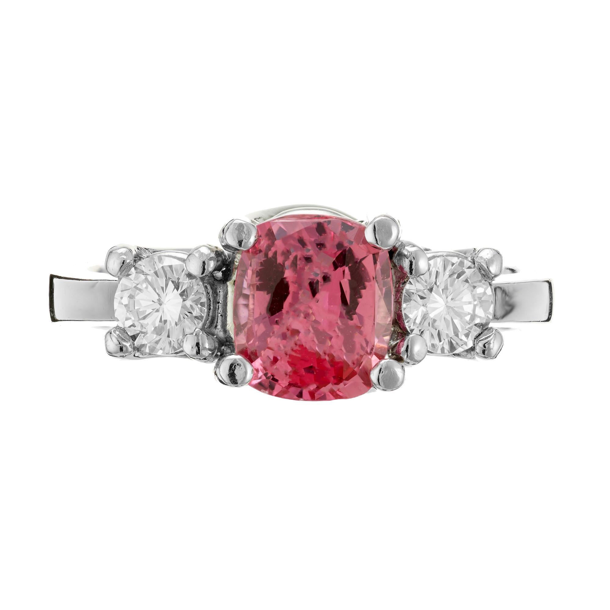 Pink Padparadscha Sapphire and diamond engagement ring. Cushion cut GIA certified center sapphire in a platinum three-stone setting with 2 round side diamonds. Small interior inclusions. 

1 cushion orangey pink Padparadscha Sapphire, approx. total