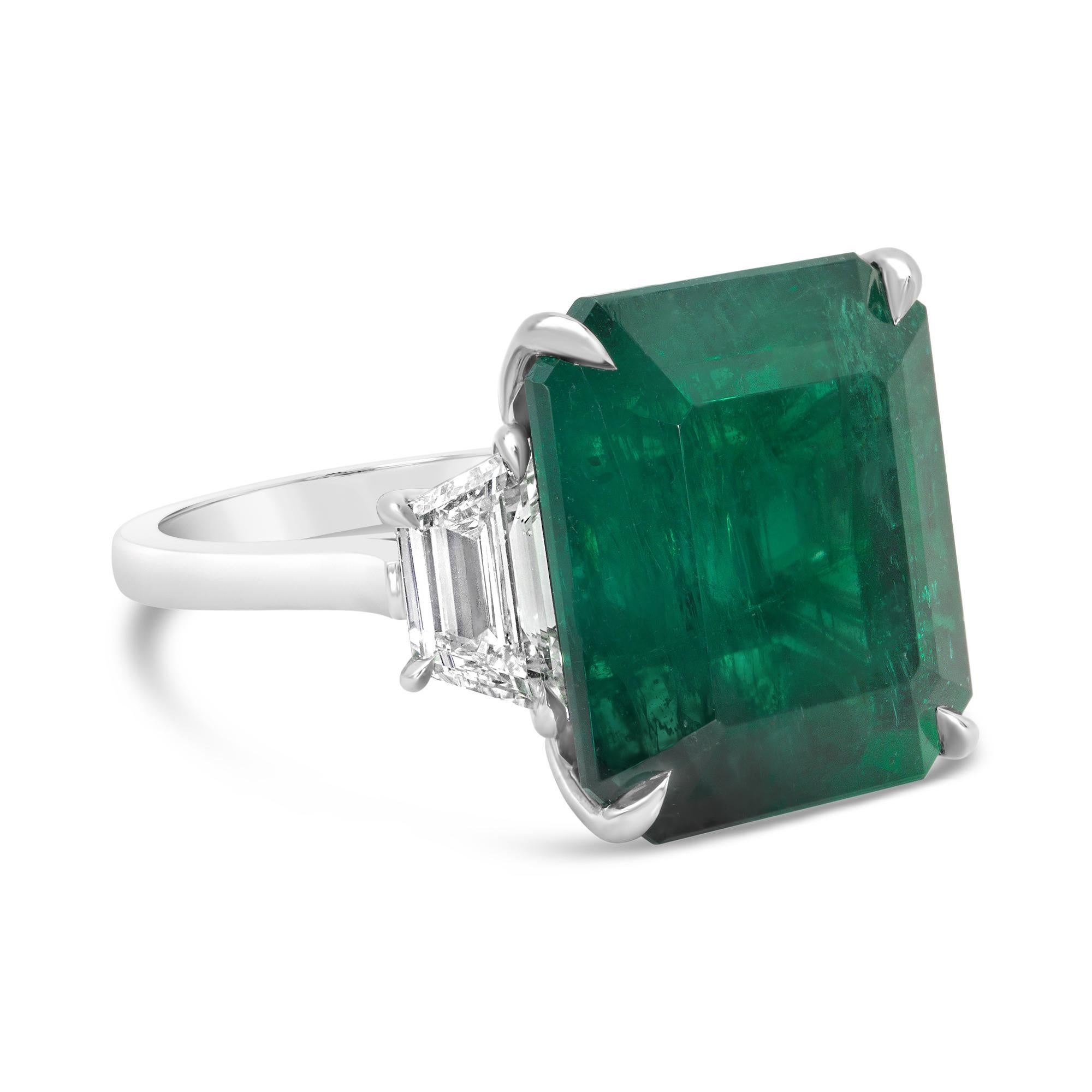 A magnificent engagement ring, featuring a C. Dunaigre certified large green emerald cut emerald weighing 16.10 carats, set on a classic four prong setting. Flanked by tapered diamonds weighing 1.44 carats total with H color and VS+ clarity.