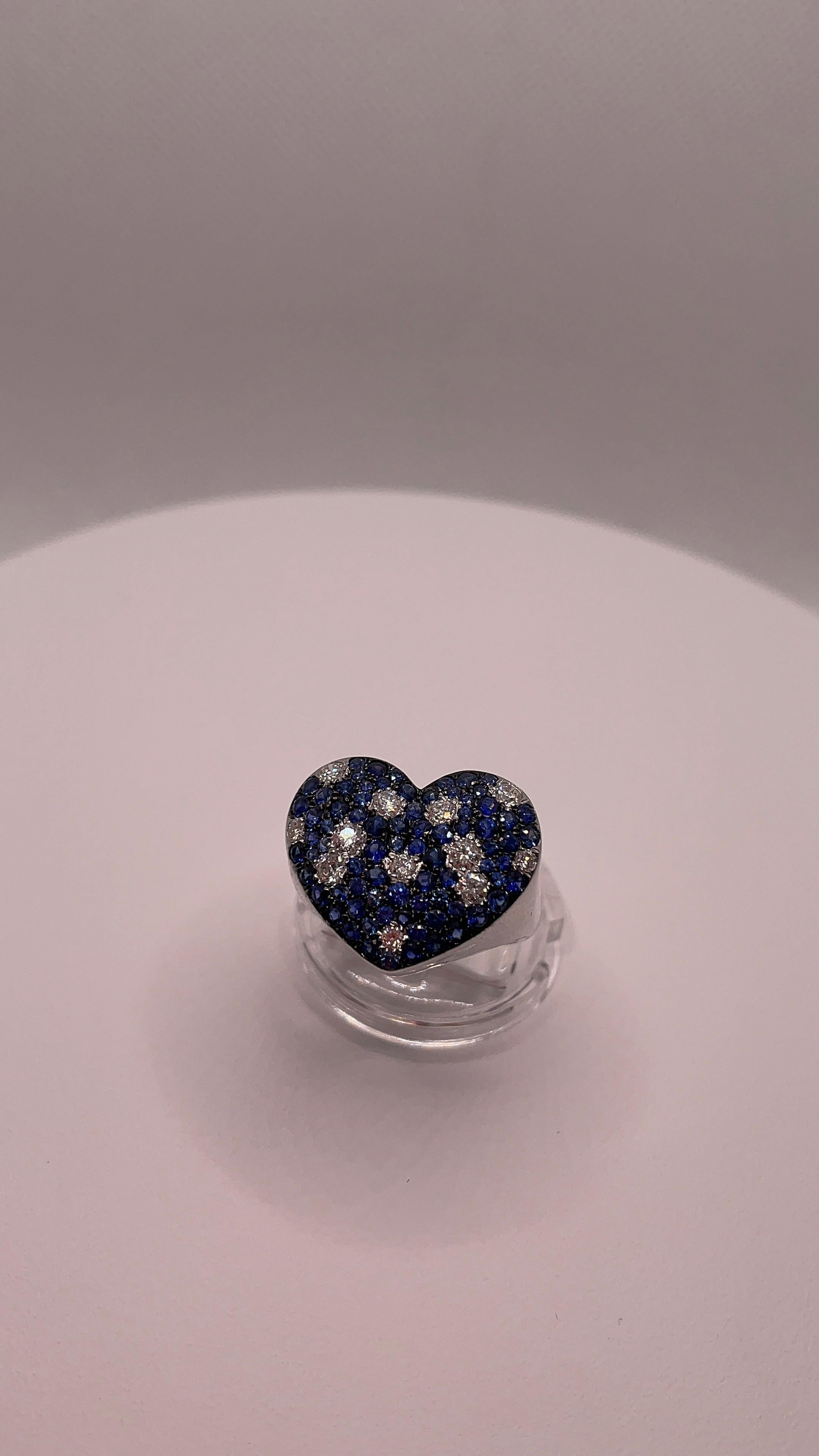 Expression audacieuse de l'�élégance et du romantisme, cette étonnante bague en forme de cœur est méticuleusement réalisée en or blanc 18 carats, pour un poids de 6,08 grammes. Sa surface est ornée d'une captivante mosaïque de 77 saphirs bleus