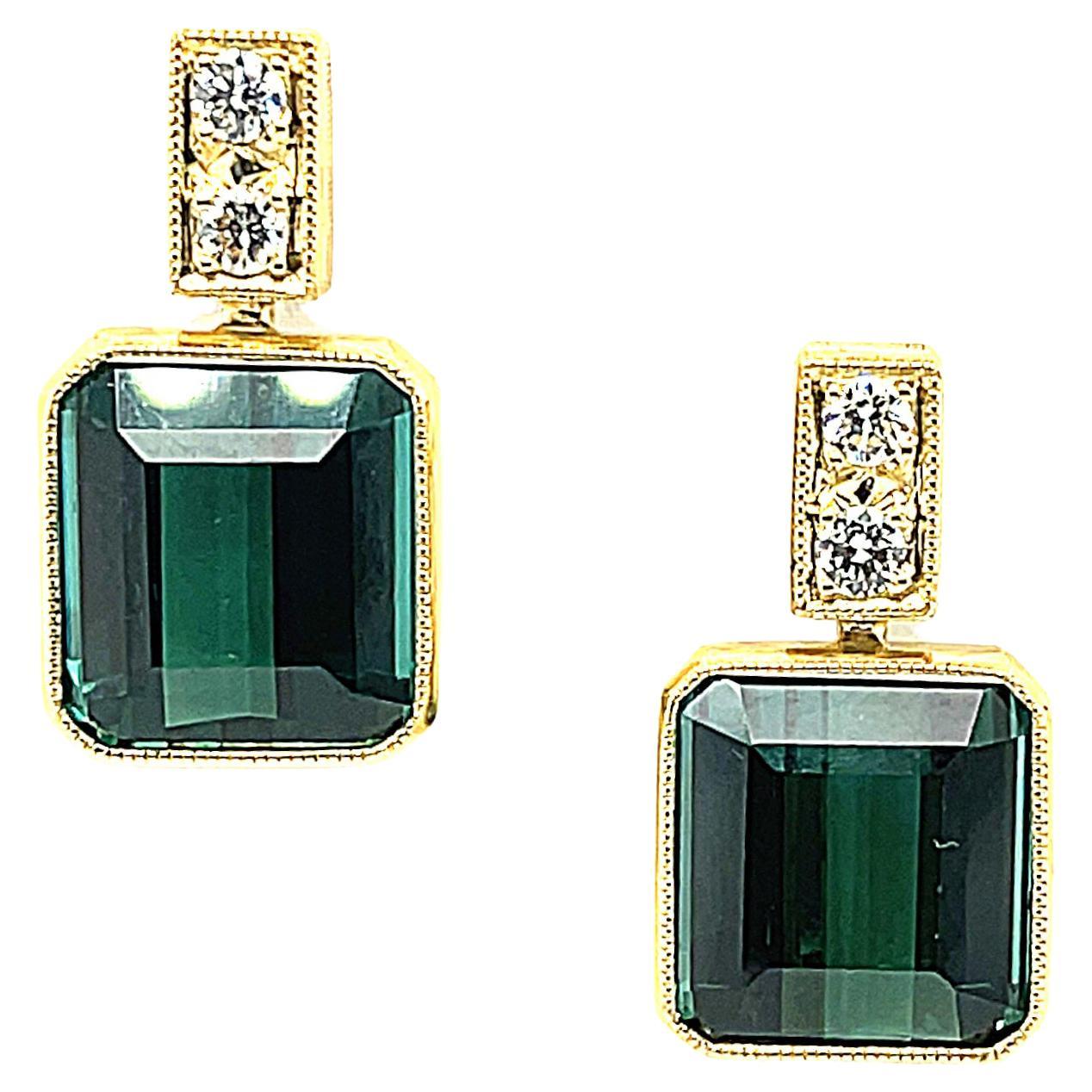 These gorgeous tourmaline and diamond earrings feature large, gem quality indicolite tourmaline with exceptional green-blue color! These gemstones are beautifully matched and so bright! They have been set in 18k yellow gold bezels that dangle from
