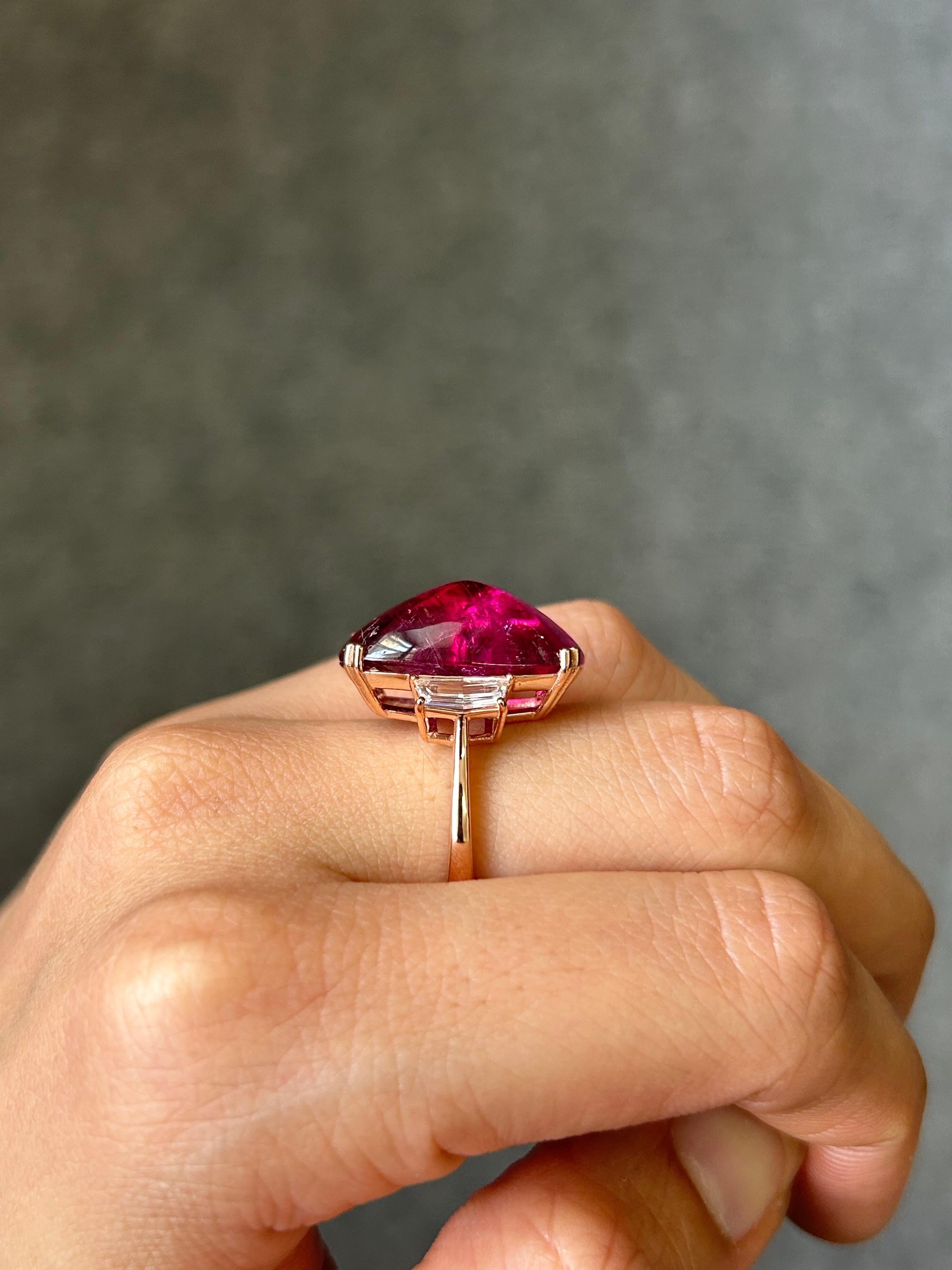 Make a statement with this unique and beautiful pink, sugarloaf shaped rubelite tourmaline and diamond three stone cocktail ring. The center stone is a certified startling pink colored natural tourmaline, weighing 16.25 carats, and the side stones