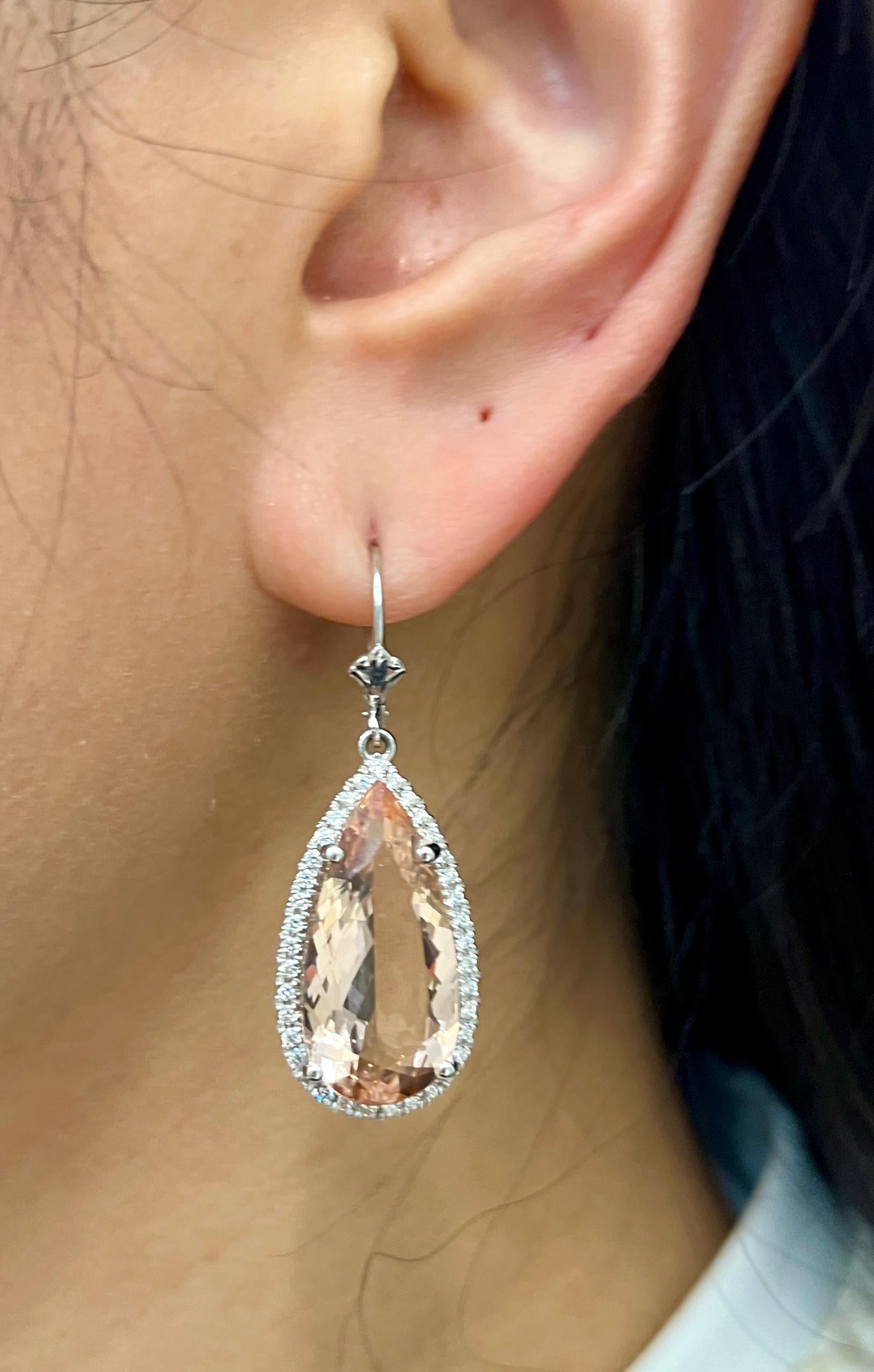 These gorgeous morganite diamond earrings feature 2 pear shape morganites weighing 15.73 ct surrounded by 74 diamonds weighing approximately 0.55 ct set in 14k white gold.
