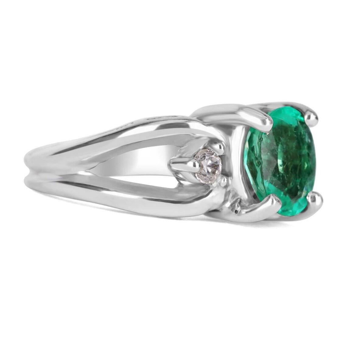 Displayed is a Colombian emerald and diamond ladies ring. Perfectly handcrafted in solid 14K white gold, this opulent ring features a bright, green Colombian emerald oval that is set in a secure four prong setting. On either side of the center stone