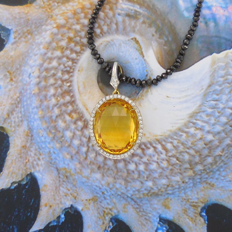 A unique pendant with a mesmerizing large Oval Citrine facetted as a Briolette and framed by a fine grain-set row of round brilliant diamonds. The sides of the pendant feature filigree patterns and add real character to this amazing pendant. The