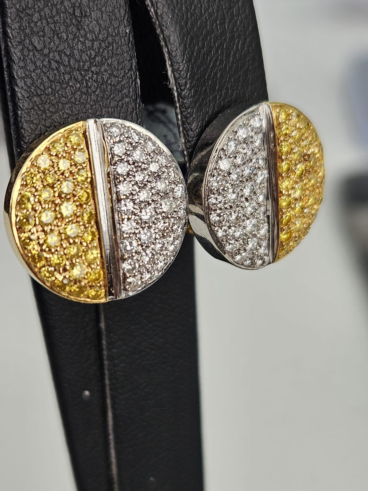 Wir präsentieren ein Paar bezaubernde Ohrringe mit 1,64 Karat kanarischem und weißem Diamanten, bei denen sich die Schönheit kontrastreicher Farbtöne und ein harmonisches Design zu einem fesselnden Kreis vereinen. Die runde Form dieser Ohrringe ist