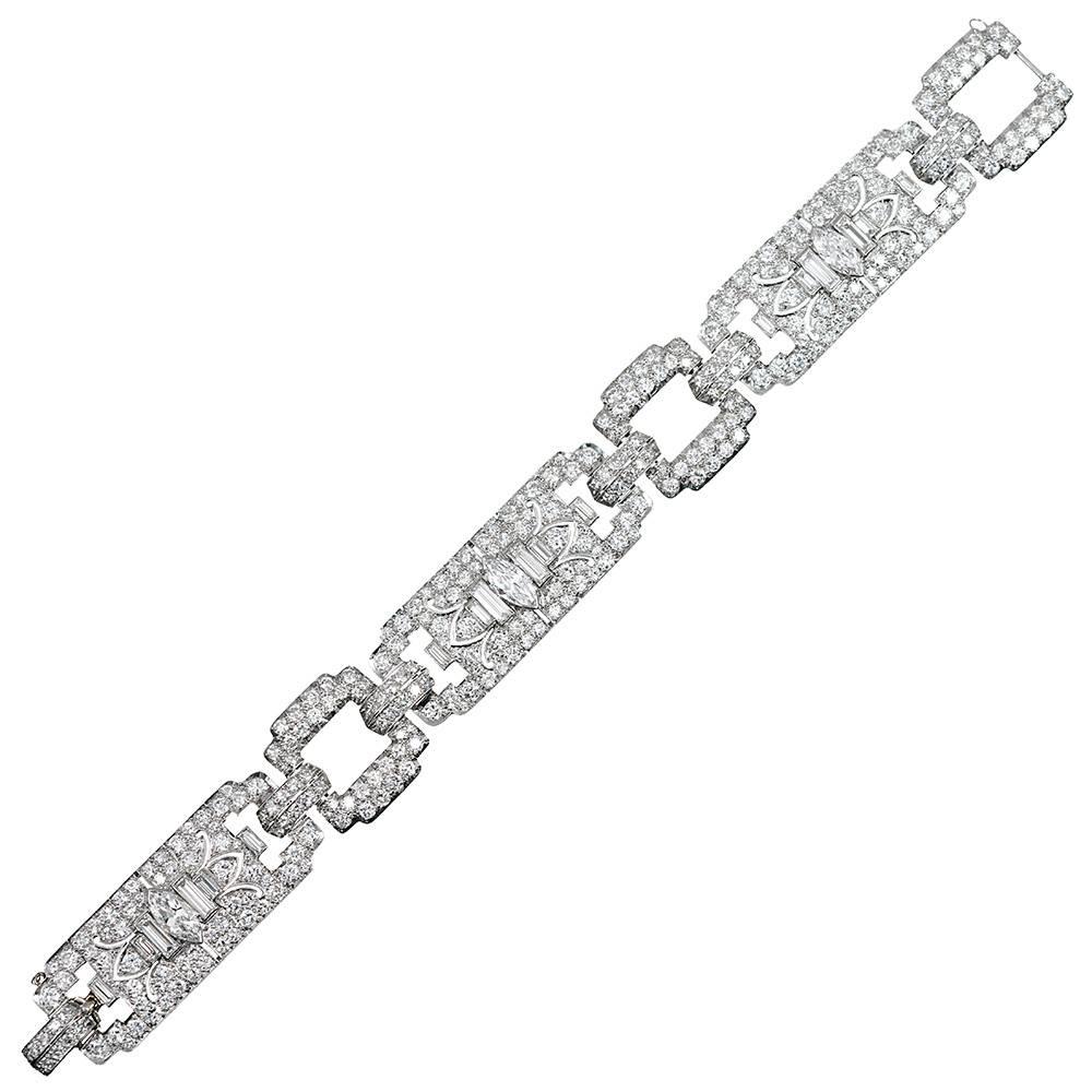 An important example of art deco craftsmanship and design, this platinum masterpiece is comprised of three major sections connected by diamond-encrusted links and double row diamond bridges. At the center of each large link is a white marquis