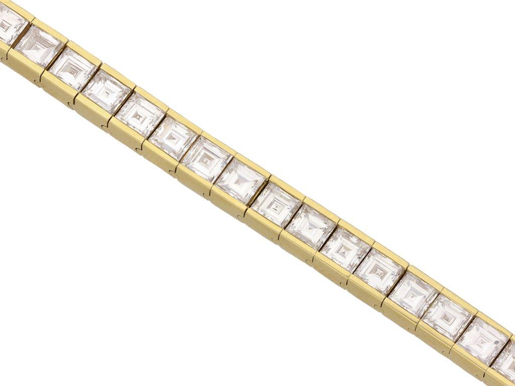 Diamond line bracelet. Set with forty one square step-cut diamonds in open back half rubover settings with a combined approximate weight of 16.40 carats, to a striking articulated line bracelet, flowing with movement, featuring polished edges, a