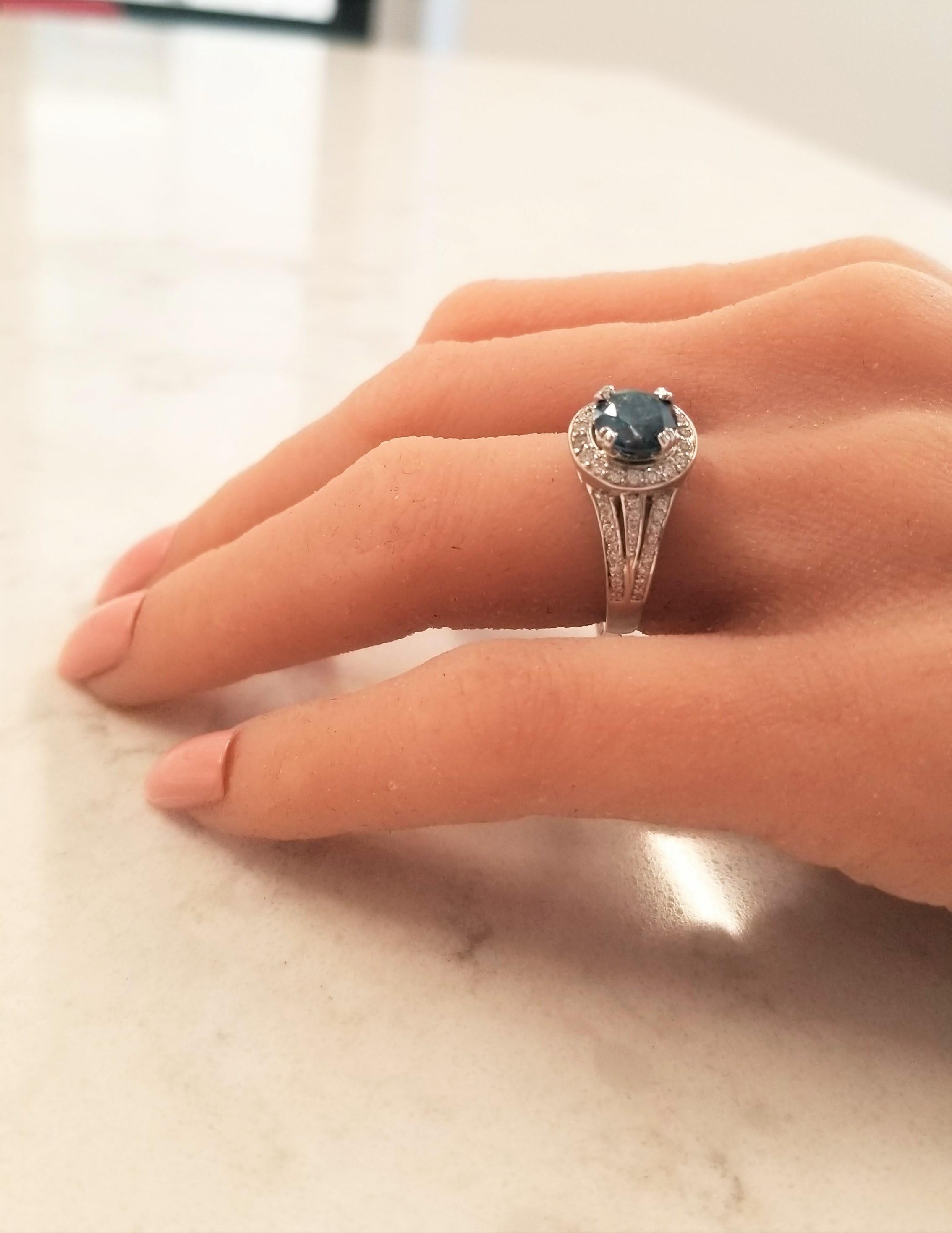 Looking for a beautiful colored gemstone that is as hard as a diamond? Your best choice is an irradiated fancy vivid blue diamond. This elegant ring features a 1.65 carat round irradiated blue diamond that is enhanced by a glittering halo of bead