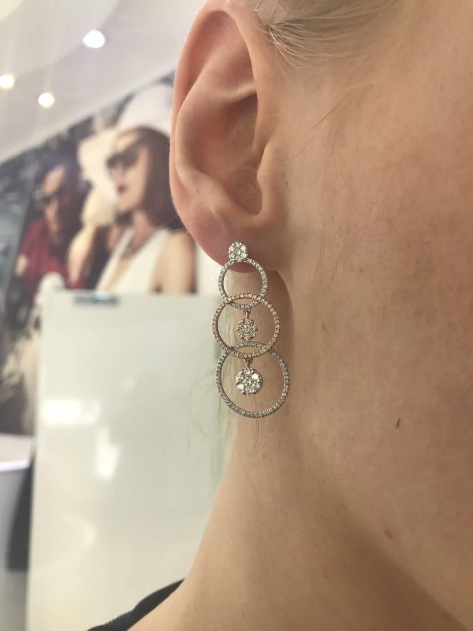 Fancy mixed 18 Karat Rose and White Gold Drop Earrings make a stylish statement with a micro set overlapping graduated hoops and clusters of Diamonds dangling effortlessly off this light weight piece. With a total of 1.65 Carats Color H Clarity SI