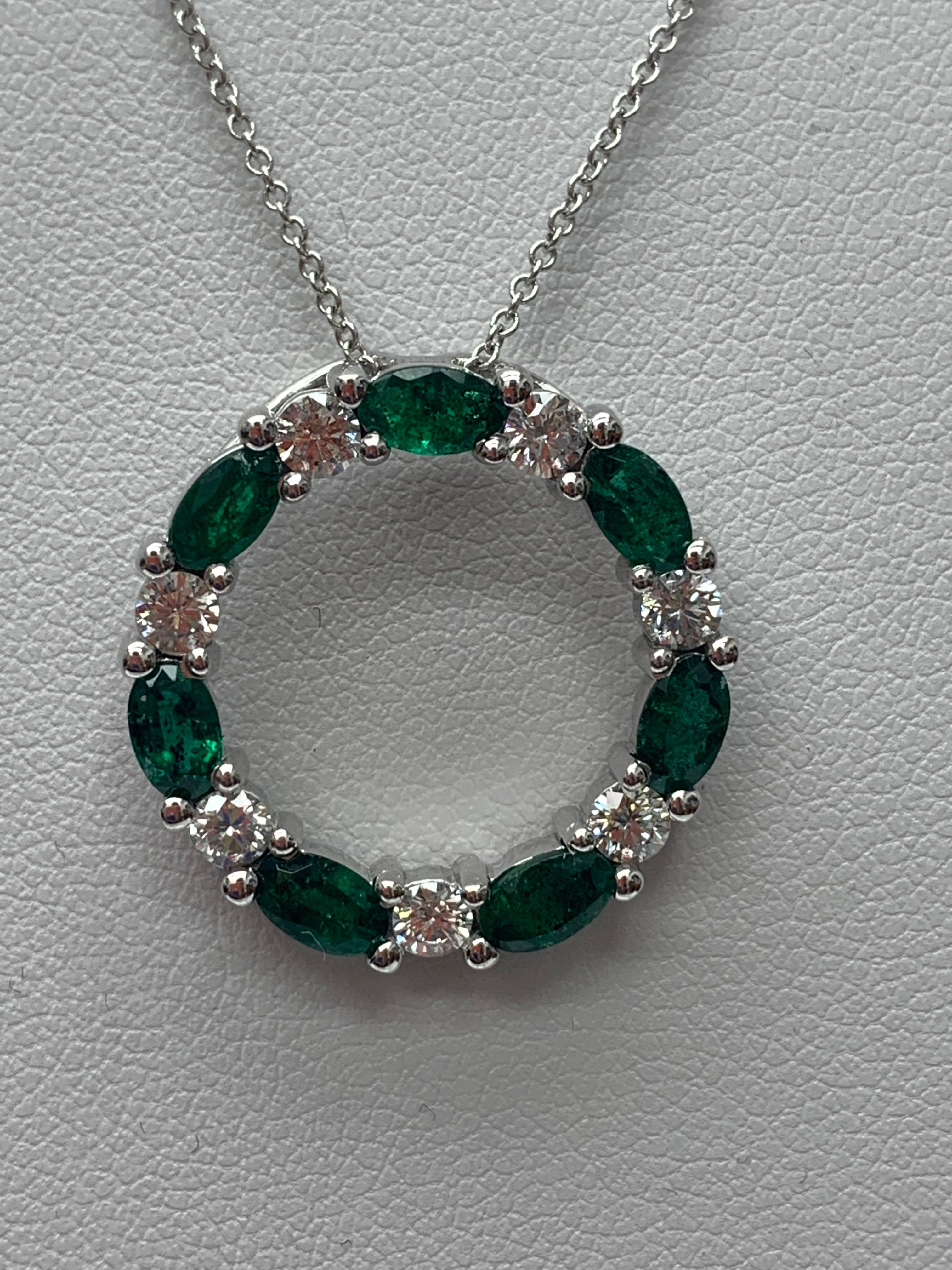 A stylish pendant necklace showcasing a row of Emerald alternating diamonds, set in an open-work, circular design. 7 oval shape emeralds weigh 1.65 carats and 7 brilliant-cut diamonds weigh 0.71 carats in total. All diamonds are GH color SI1