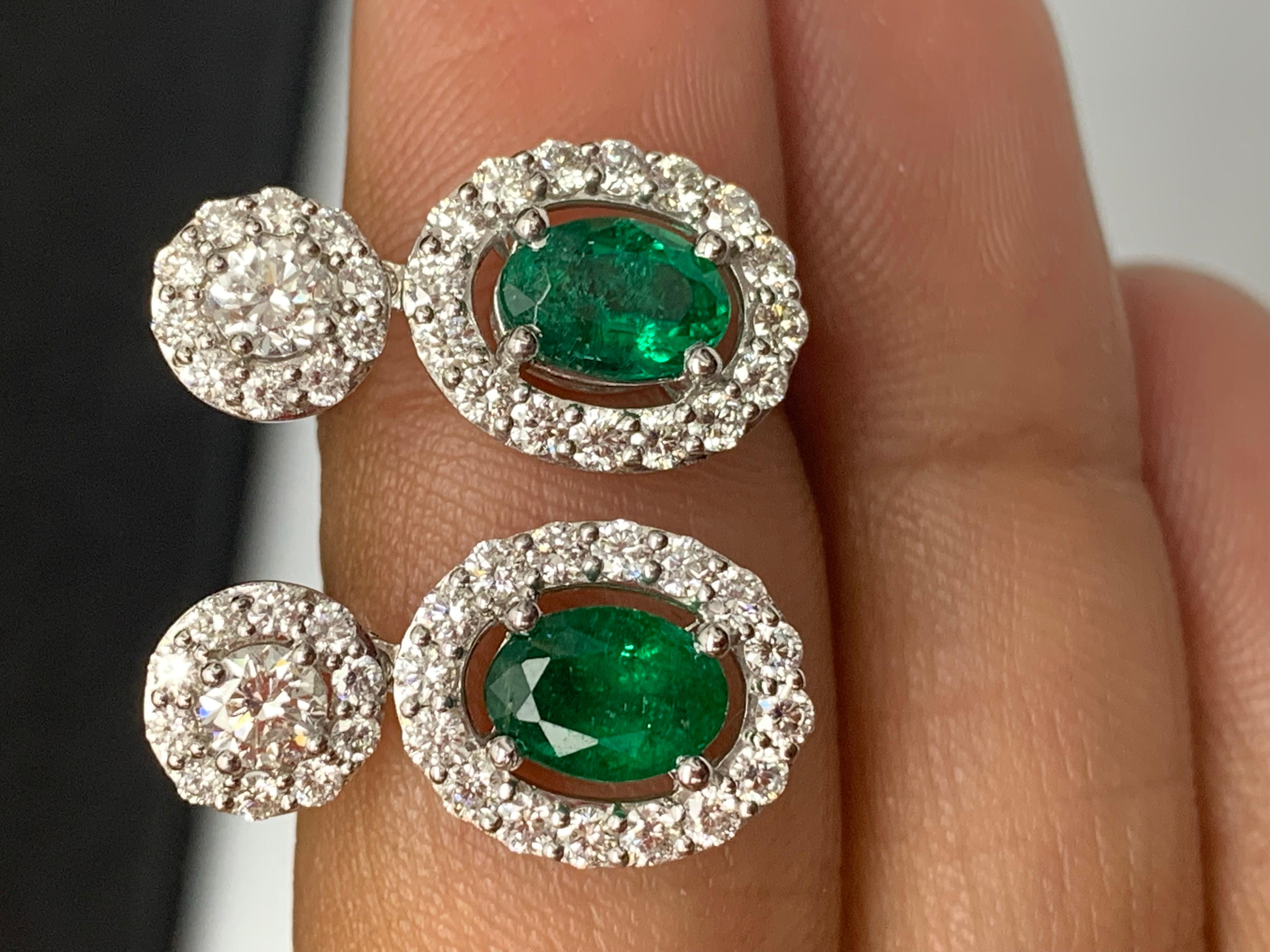 Une belle et chic paire de boucles d'oreilles pendantes mettant en valeur des diamants de taille brillante et des émeraudes de forme ovale, le tout serti dans un design complexe et élégant. 2  Les diamants de la partie supérieure pèsent 0,37 carat