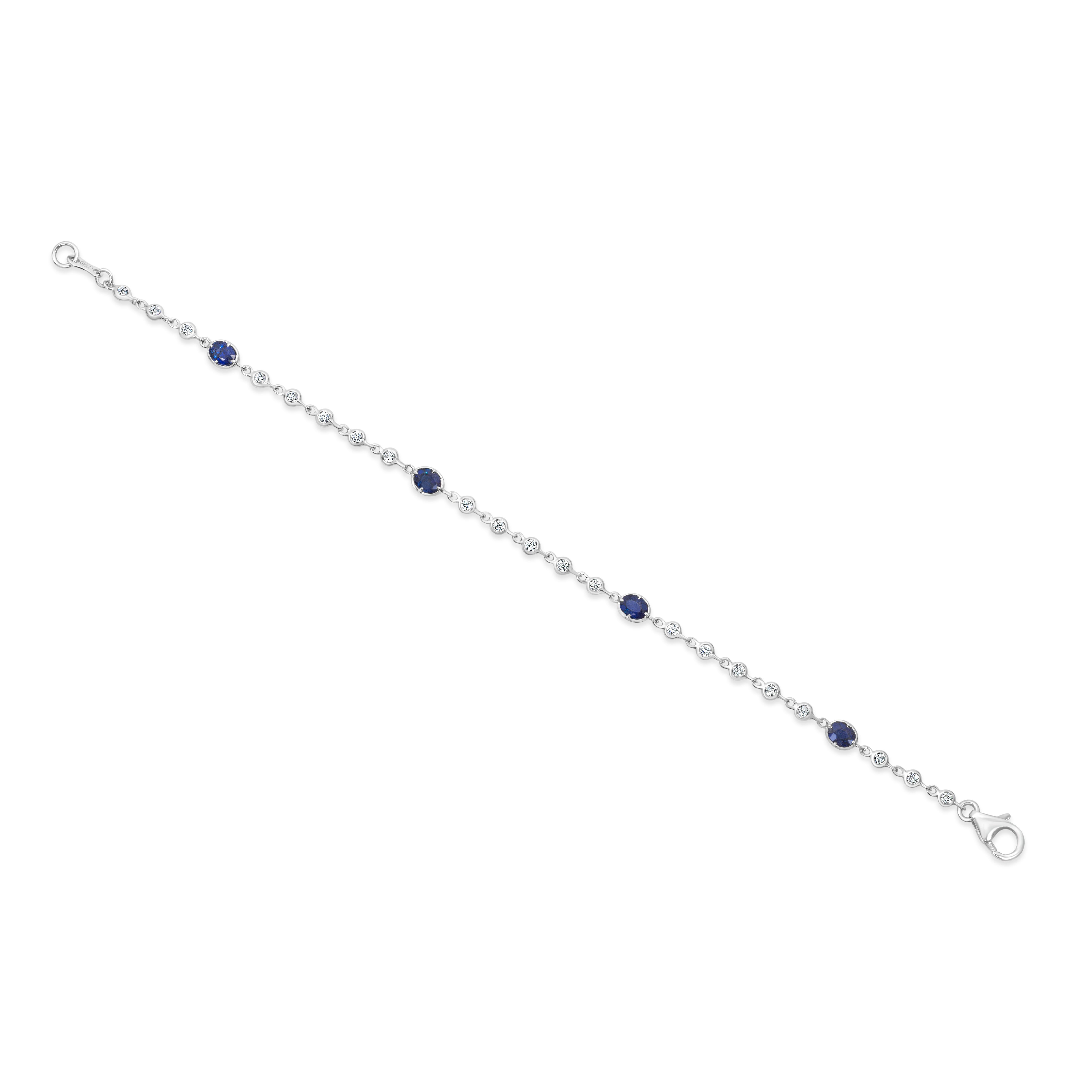 A fashionable bracelet, featuring oval cut sapphires weighing 1.24 carats total, each set on a four prong bezel. Accented by bezel-set round cut diamonds weighing 0.41 carat total. Finely made with 18K white gold, 7 inches in length. Perfect for