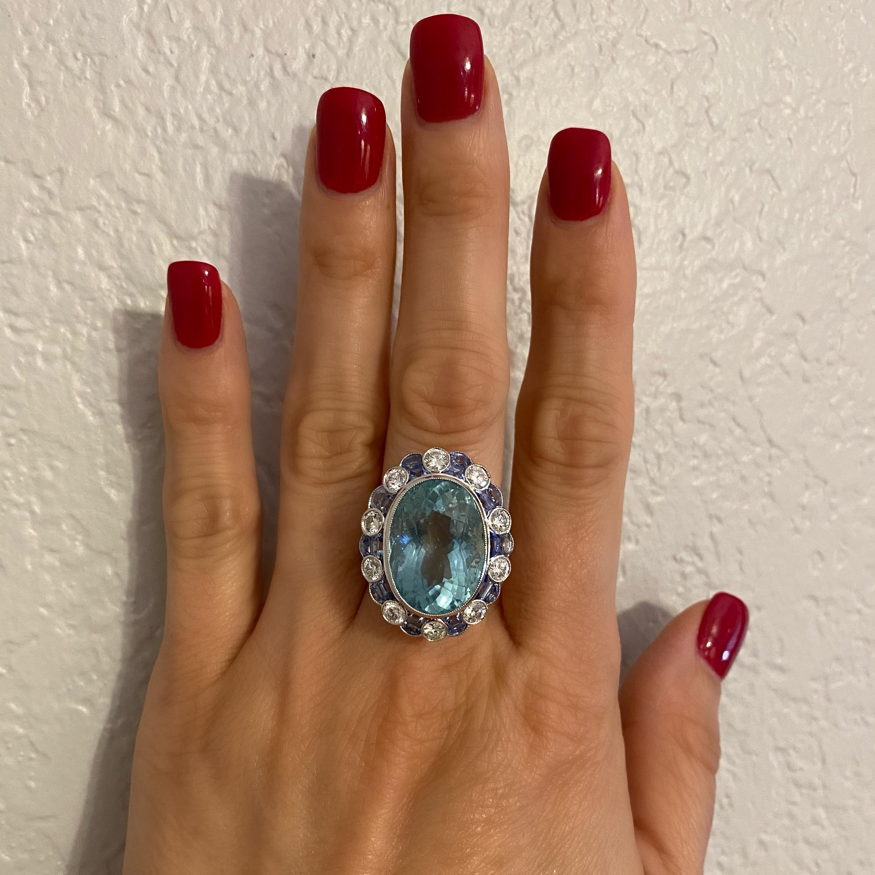 Beautiful and finely detailed Platinum Art Deco Style Ring, center Hand set with a securely nestled 16.50 Carat oval Aquamarine Gemstone surrounded by 20 custom cut blue Sapphires, approx. 3.00tcw and 16 round Brilliant cut Diamonds, approx.