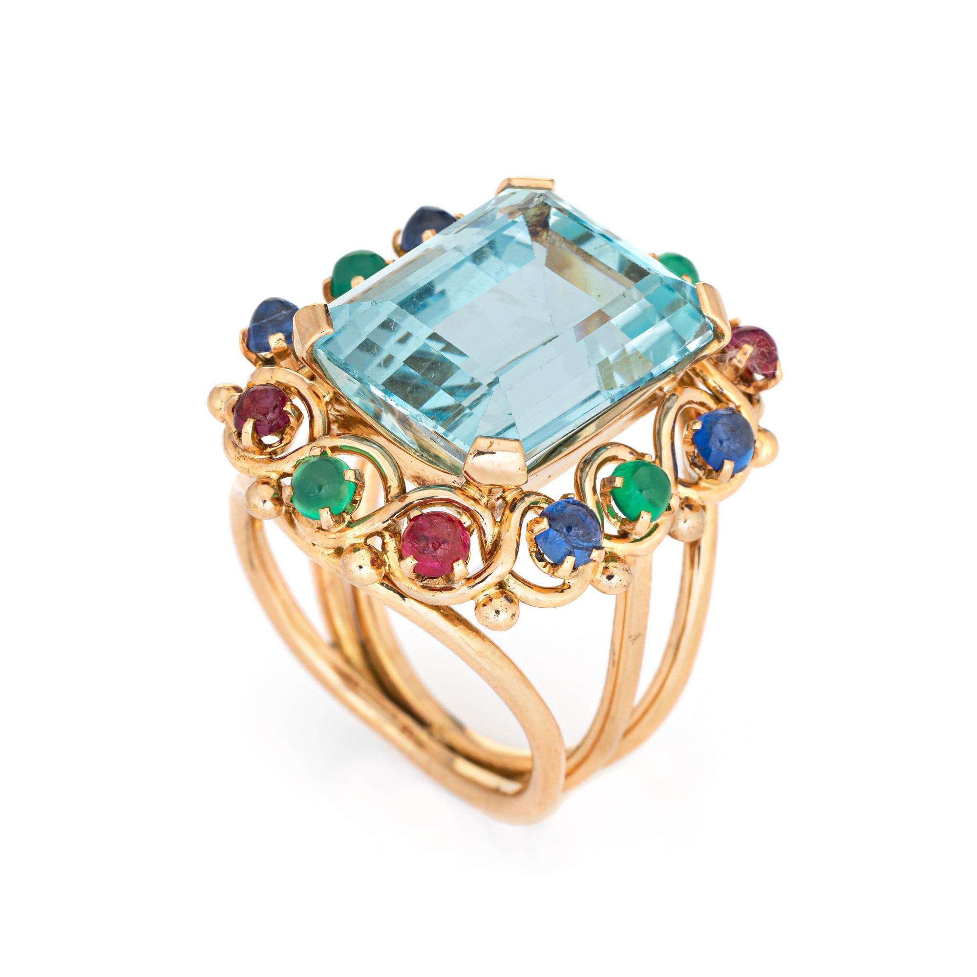 Stylish vintage aquamarine & emerald cocktail ring (circa 1950s to 1960s) crafted in 14 karat yellow gold. 

Emerald cut aquamarine measures 16.5mm x 14mm (estimated at 16.50 carats), accented with an estimated 1.80 carats of cabochon cut emeralds,