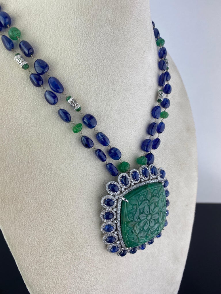 An art-deco style, hand carved 165.32 carat natural Emerald pendant, surrounded with 24.87 carat Blue Sapphire cabochons and 5.65 carat White Diamonds, all set in 40 grams of solid 18K White Gold. The chain consists of 377 carat Blue Sapphire tumble