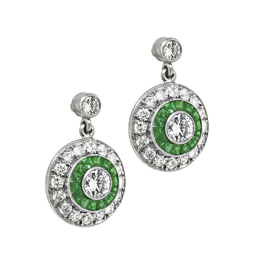 This is a charming pair of platinum earrings. The earrings feature sparkling round cut diamonds that weigh approximately 1.65ct. The color of the diamonds is G with VS clarity. The diamonds are accentuated by lovely emerald accents. The earrings