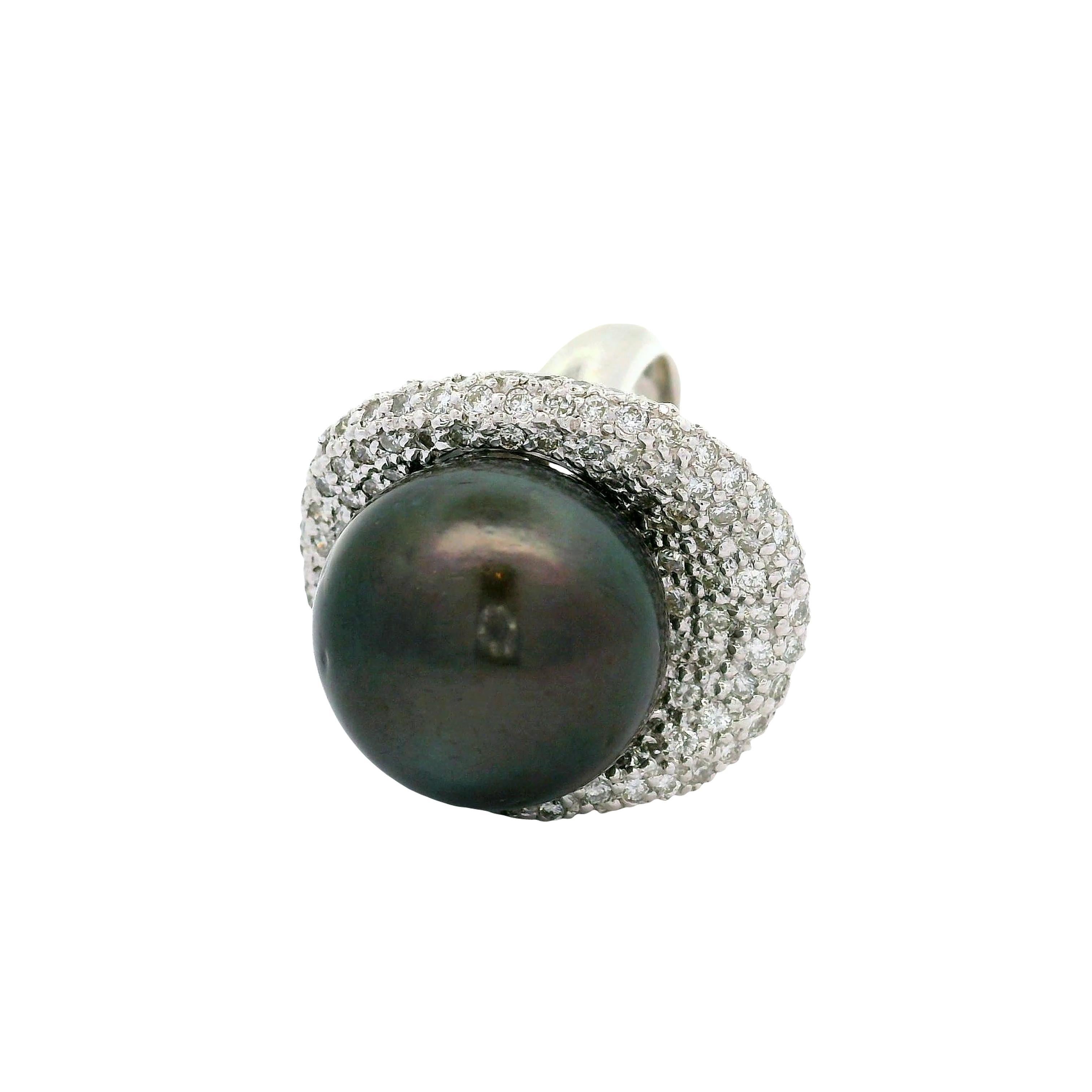 Cette bague remarquable est ornée d'une perle noire de Tahiti, taillée en forme de boule lisse, d'environ 16,5 mm. La teinte noire profonde de la perle est complétée par un halo de diamants blancs ronds, totalisant 2,27 carats. Ces diamants ajoutent