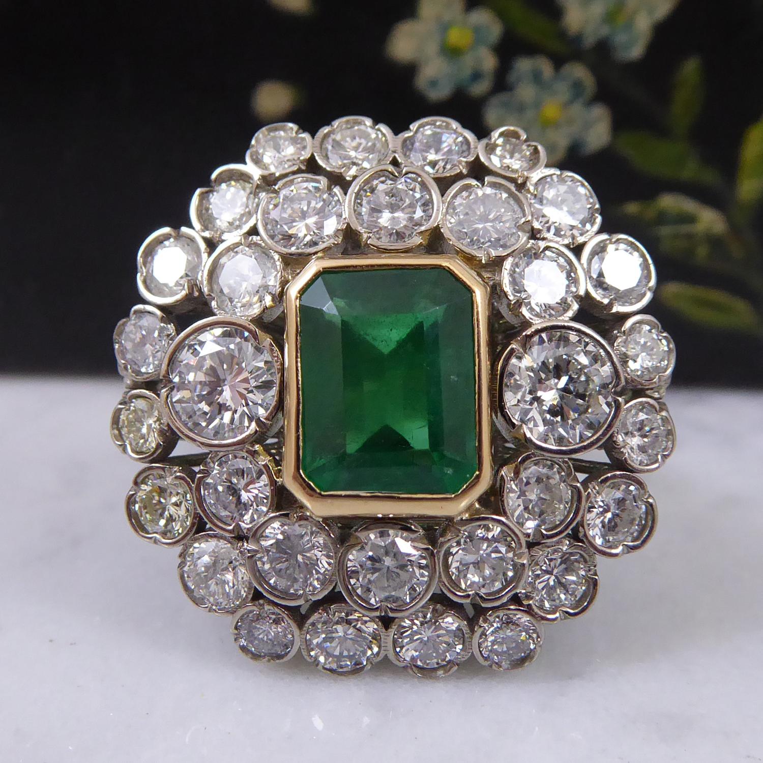 A spectacular emerald and diamond cocktail cluster ring.  The ring is set to the centre with a octagonal step cut, medium to dark green emerald, measuring approx. 8.20mm x 5.80mm 4.76mm deep, with an estimated weight of 1.66ct.  A double border of