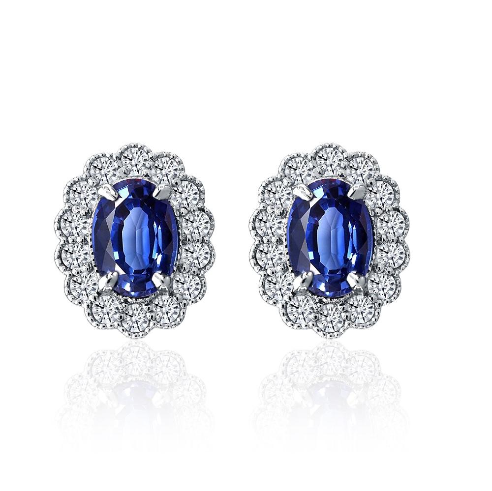 These earrings boast elegance and sophistication, featuring exquisite 7mm x 5mm oval sapphires totaling 1.66 carats. The sapphires are beautifully accented by a halo of round white diamonds, adding a touch of brilliance with a total weight of 0.45