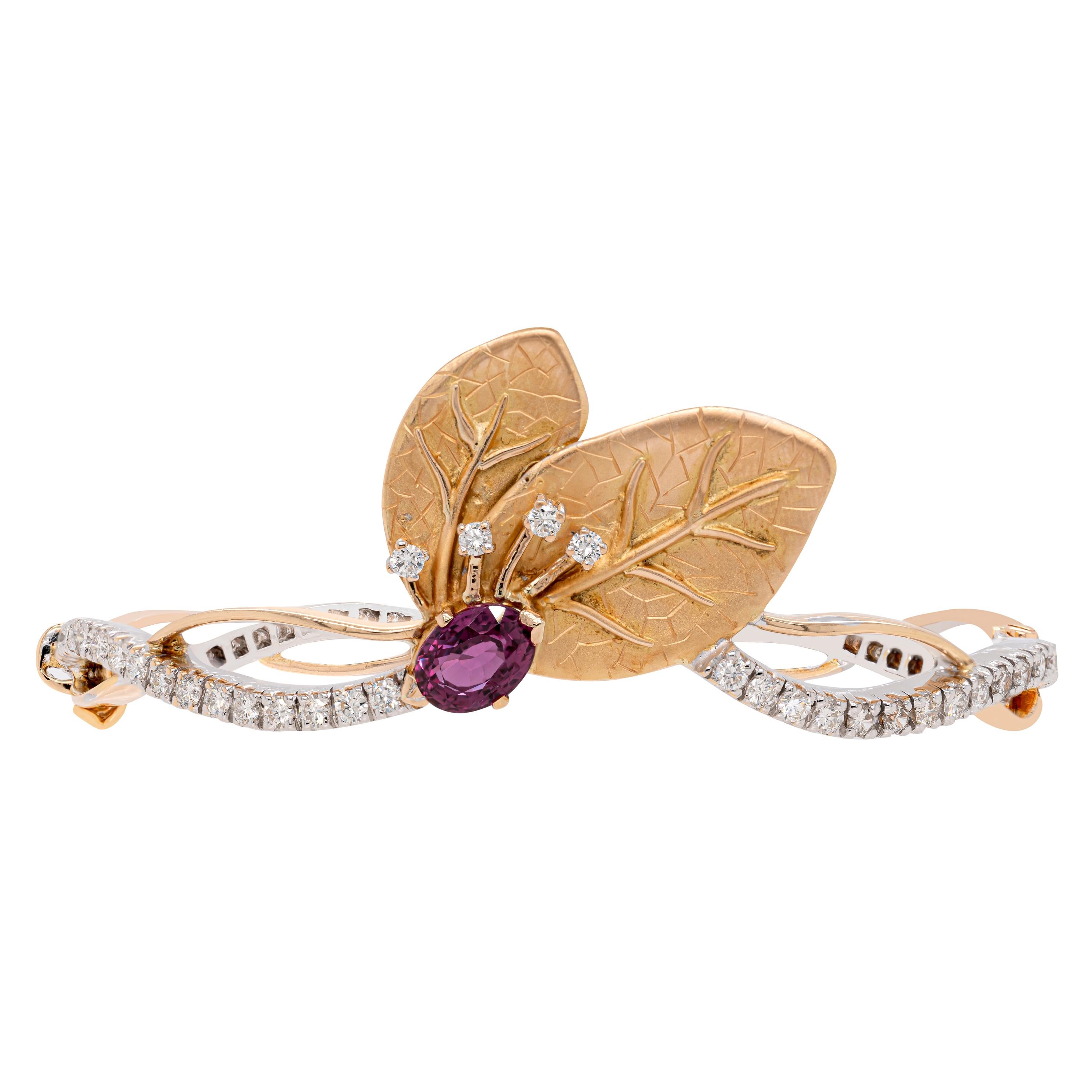 This gorgeous 18 carat gold bangle features a 1.66ct oval shaped pink tourmaline in the centre, highlighted by two beautifully detailed solid yellow gold leaves which are decorated with a spray of four round brilliant cut diamonds. The bangle's