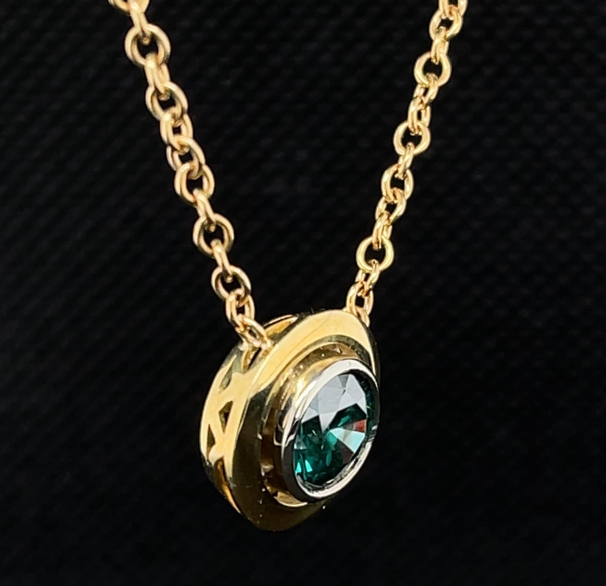 This eye-catching necklace features a stunning 1.66 carat round blue diamond set in an 18k white gold bezel with an 18k yellow gold bezel halo. This polished gold pendant is suspended from an 18k yellow gold chain, allowing the center diamond to