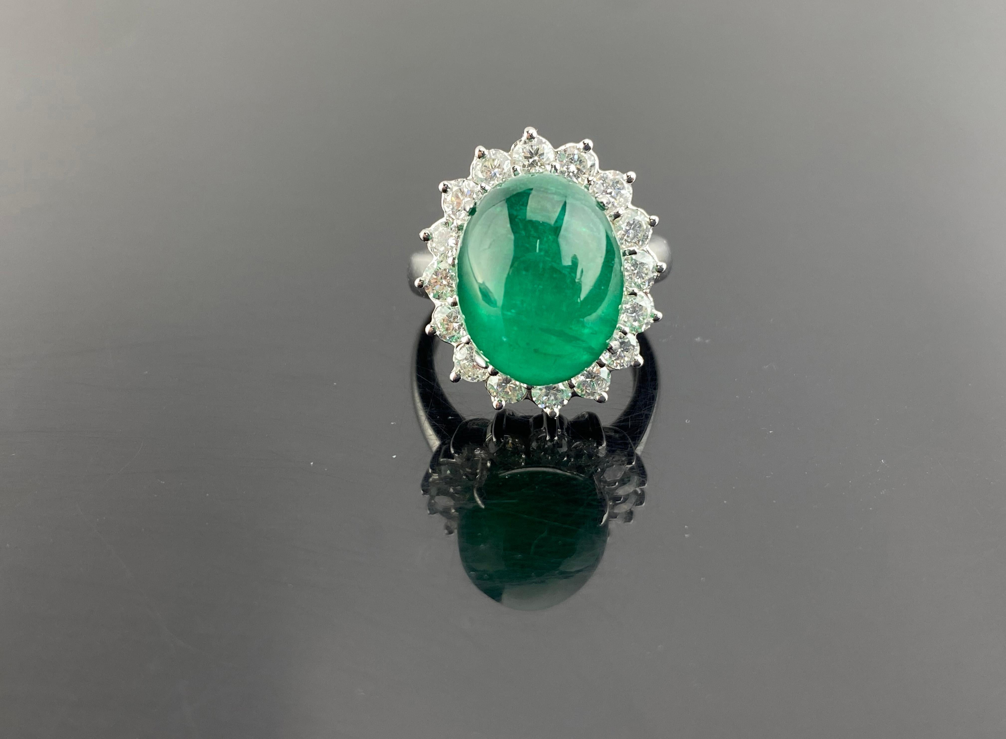 A beautiful, classic 16.60 carat Zambian Emerald cabochon center stone, with 1.04 carat VS quality White Diamonds around it, all set in 18K solid White Gold. The Emerald is transparent, lustrous and of an ideal vivid green color, making it a very