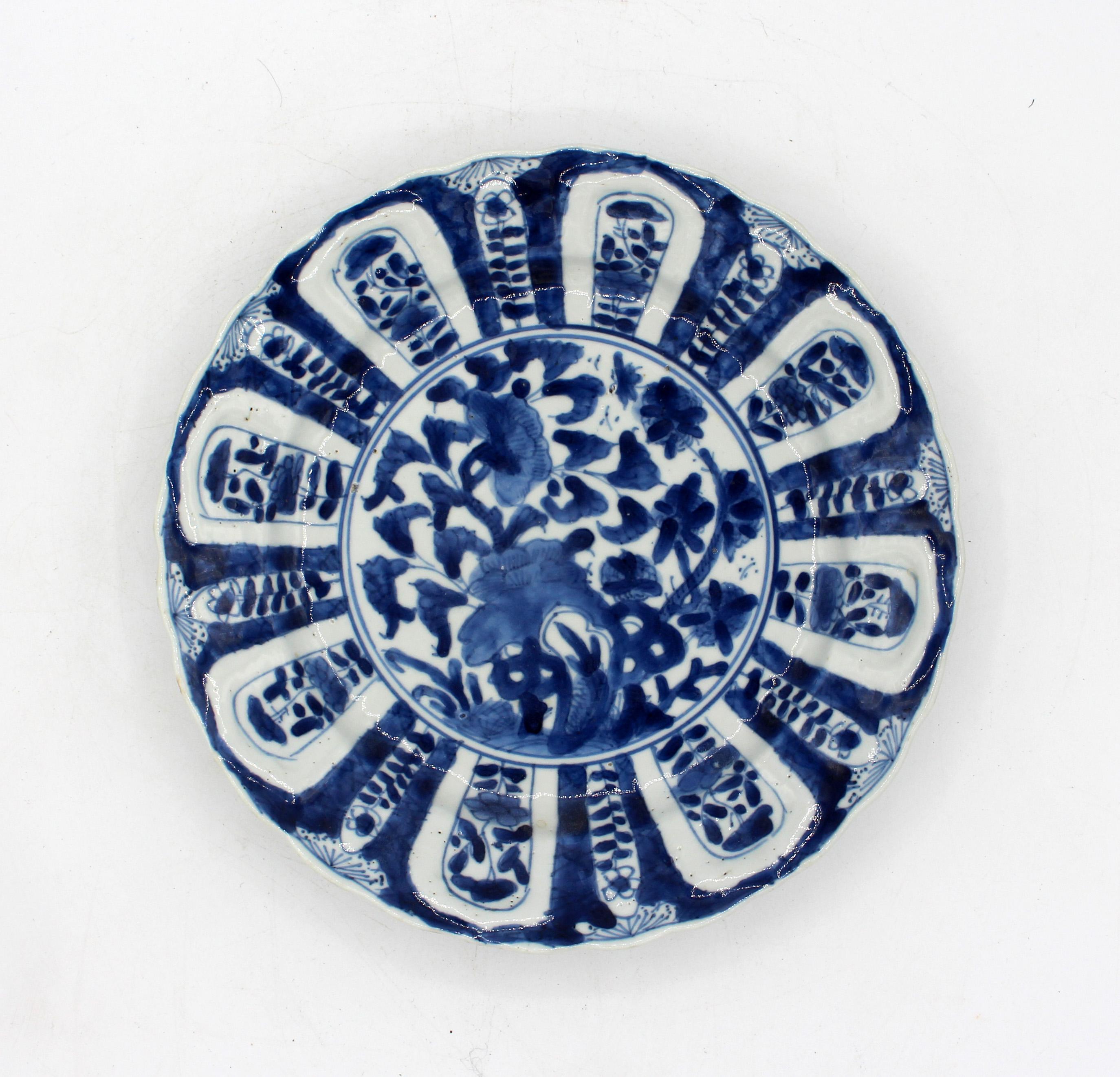 1662-1722 Zugehöriges Paar blau-weißer Porzellanteller, chinesisch. Kangxi-Periode. Geformte Körper mit Reserven in Form von Lotusblüten. Die 8-flutigen geformten Seiten umgeben ein Reservat von blühenden Pflanzen, die aus einem Taihu-Felsen
