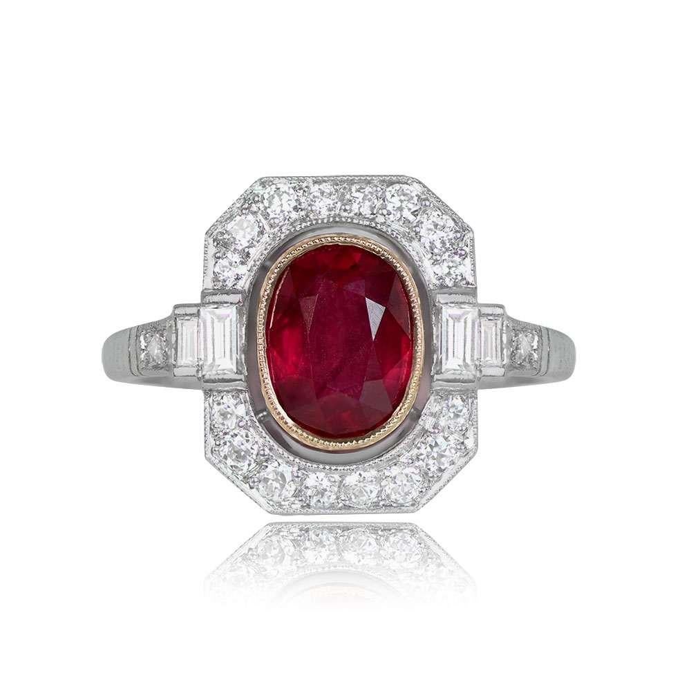 A magnificent gemstone ring with a central 1.66-carat oval-cut ruby, set in an 18k yellow gold bezel. It is adorned with a geometric halo of old mine-cut diamonds, and additional diamonds accent the shoulders and shank, with a total diamond weight