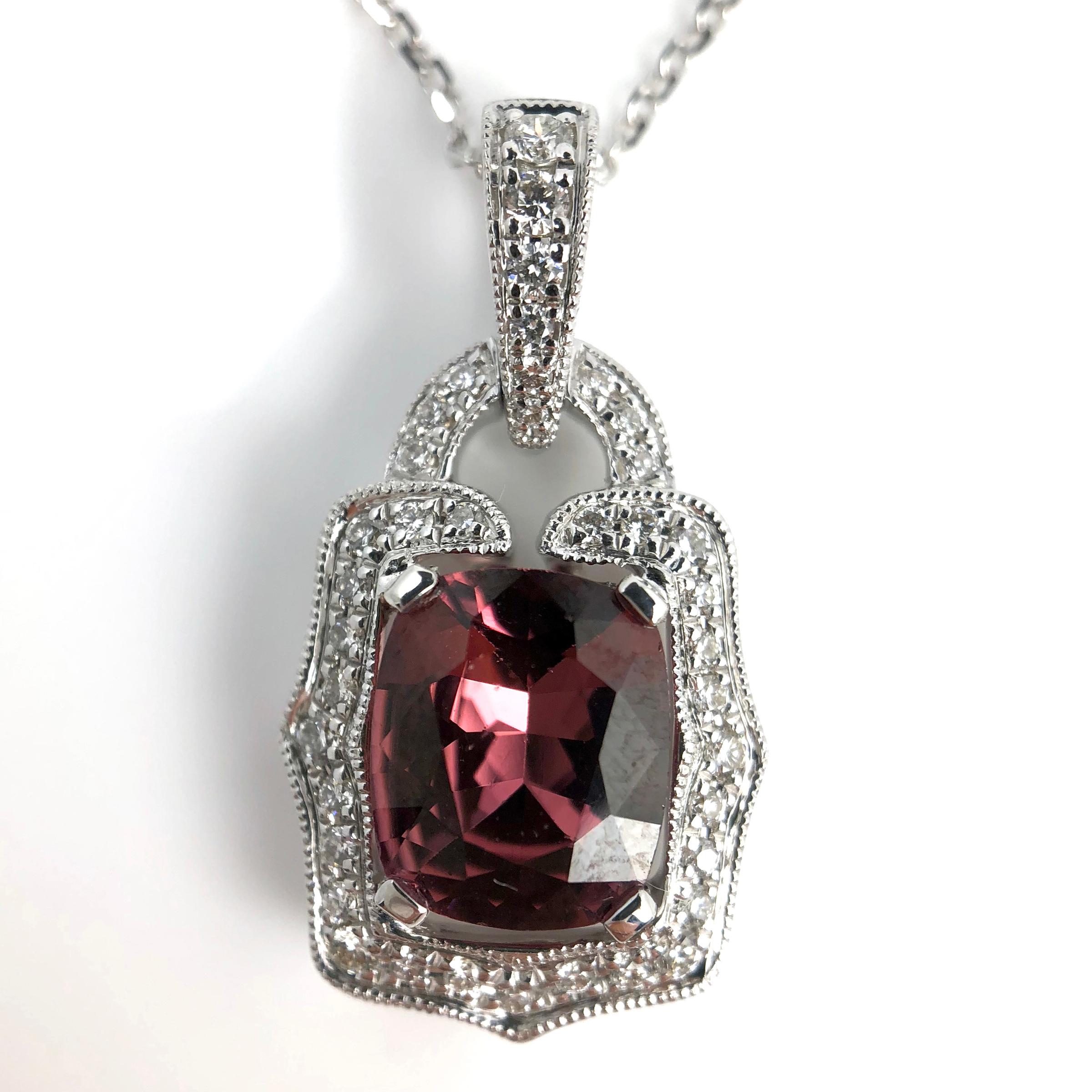 This pendant features a 1.67 carat cushion cut raspberry garnet, surrounded by 0.19 carats round white diamonds, in an antique lock shape, including a decorated bail.

Center: 1.67 carats cushion cut raspberry purple-pink garnet
Total diamond weight