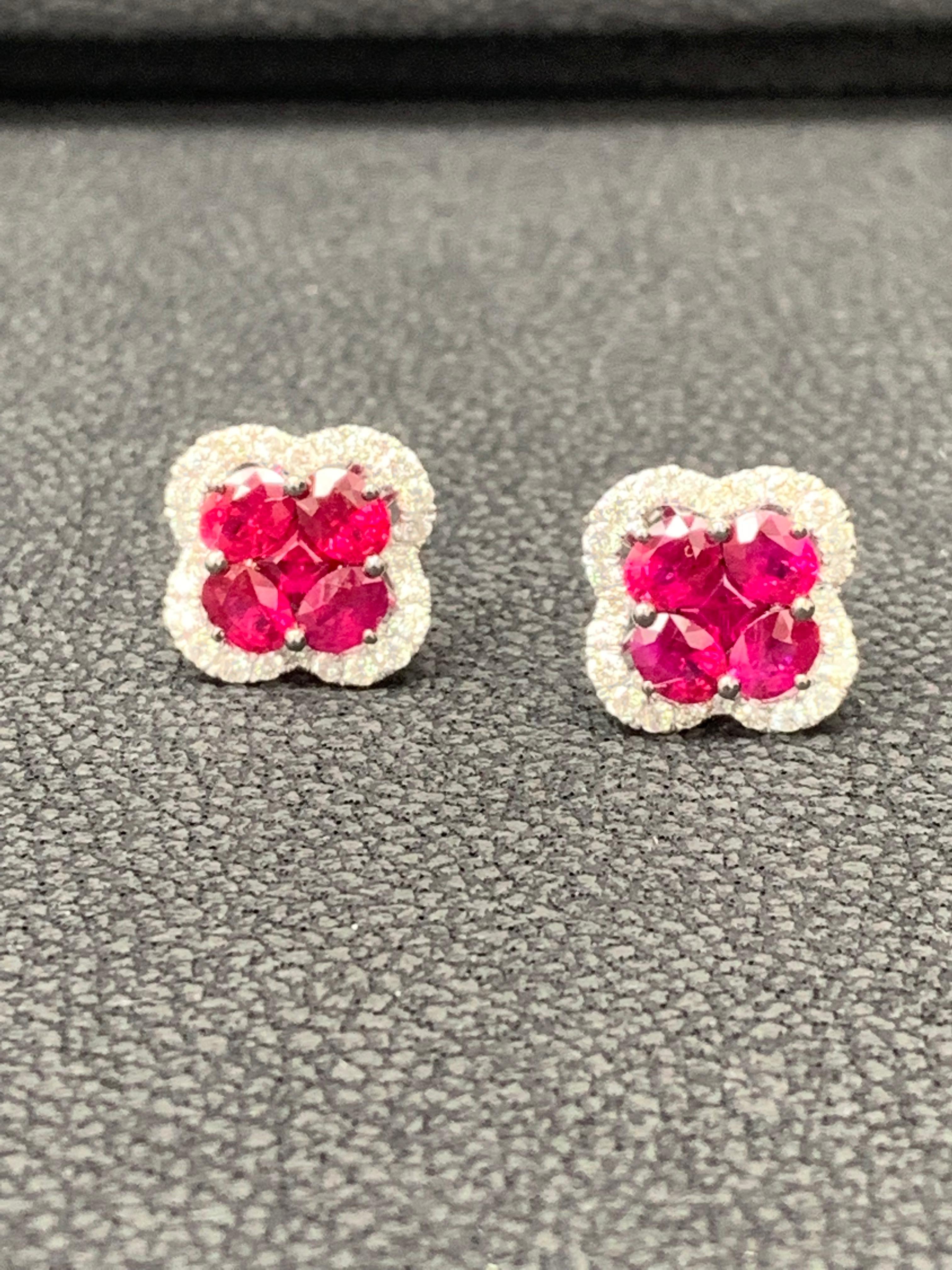 Showcasing flower design stud earrings with 8 oval shape Rubies weighing 1.67 carats total and 2 round shape rubies weighing 0.19 carat, accented by a row of round brilliant diamonds. Diamonds weigh 0.40 carats total. Set in a polished 18K white