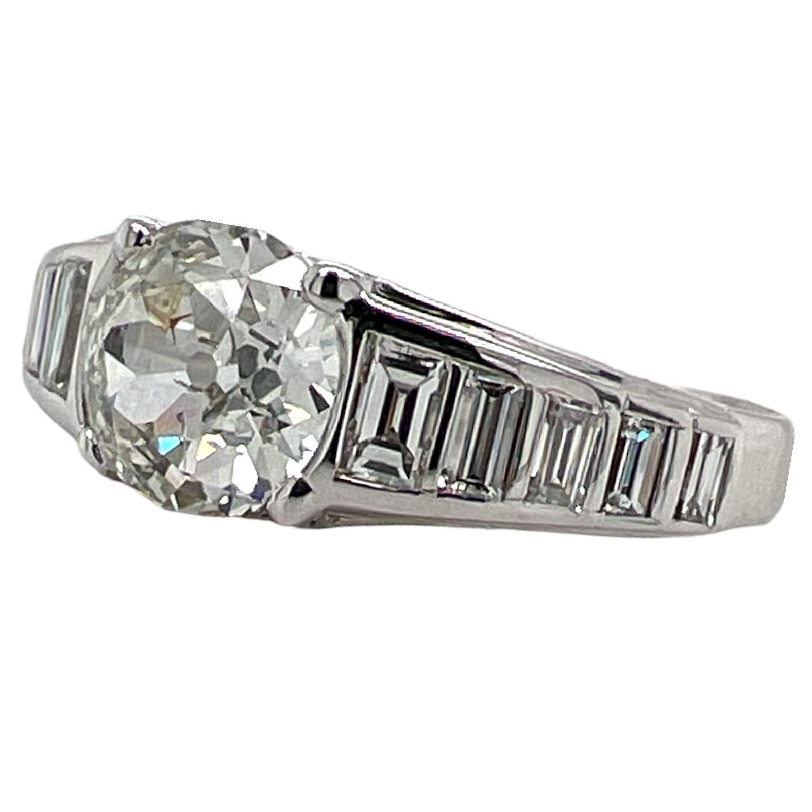 Estate diamond engagement ring crafted in platinum. The ring features an approximately 1.67 carat Old European cut diamond graded J-K color and SI clarity. The platinum mounting is set with 10 baguette diamonds weighing approximately .60 CTW. The