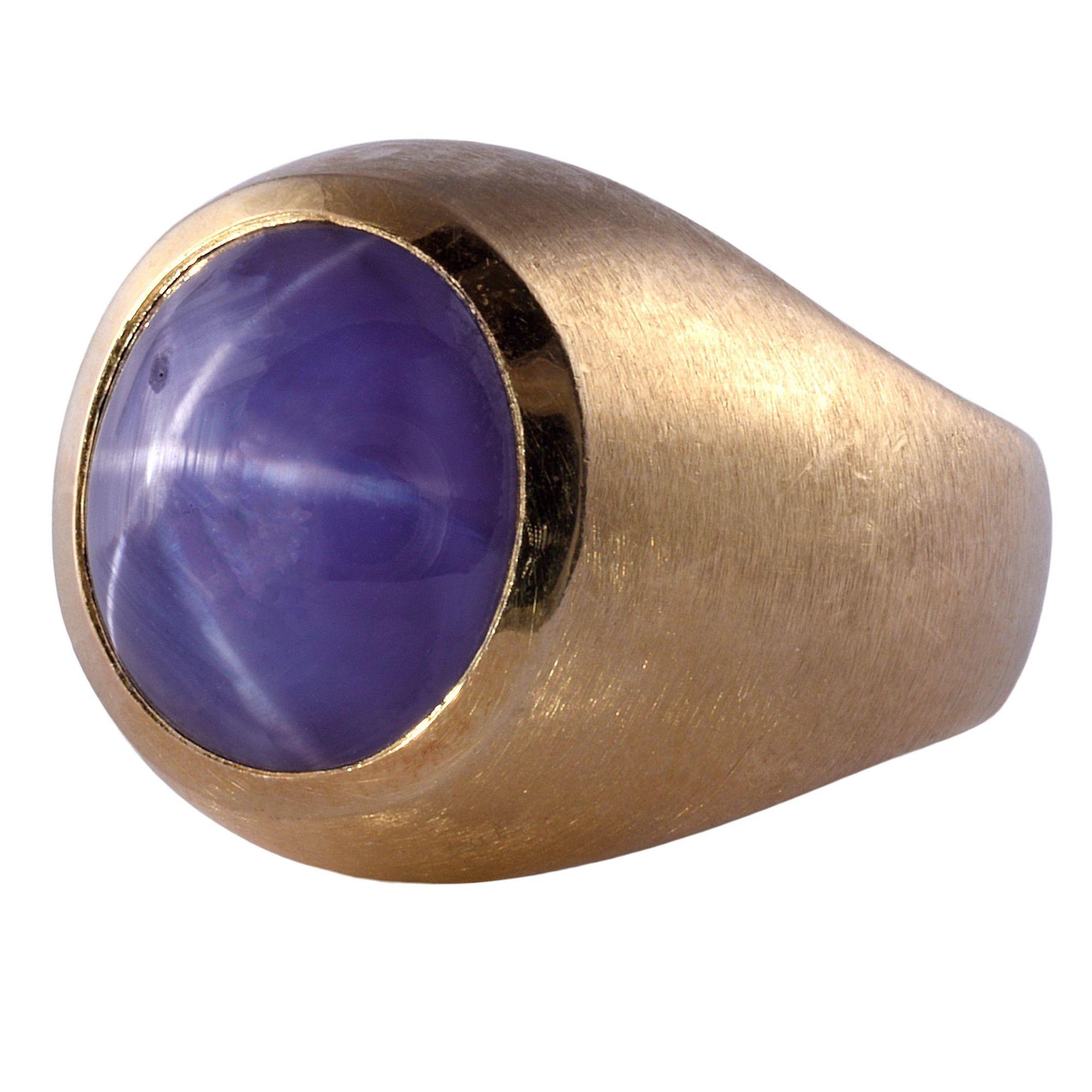 Vintage 16.75 carat purple star sapphire mens ring, circa 1980. This vintage mans ring is crafted in 18 karat yellow gold with a brushed finish. The vintage ring features a 16.75 carat purple star sapphire with nice color and a very good star. This