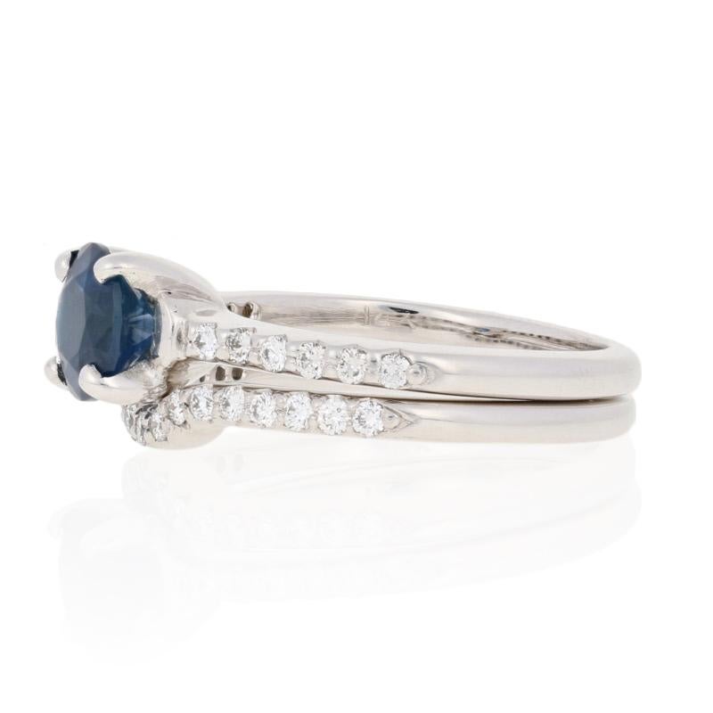 Begin the next chapter of your unique love story with this stunning bridal set! Consisting of an engagement ring and a matching guard-style enhancer wedding band, this 14k white gold set hosts a satin blue sapphire accompanied by a sparkling array