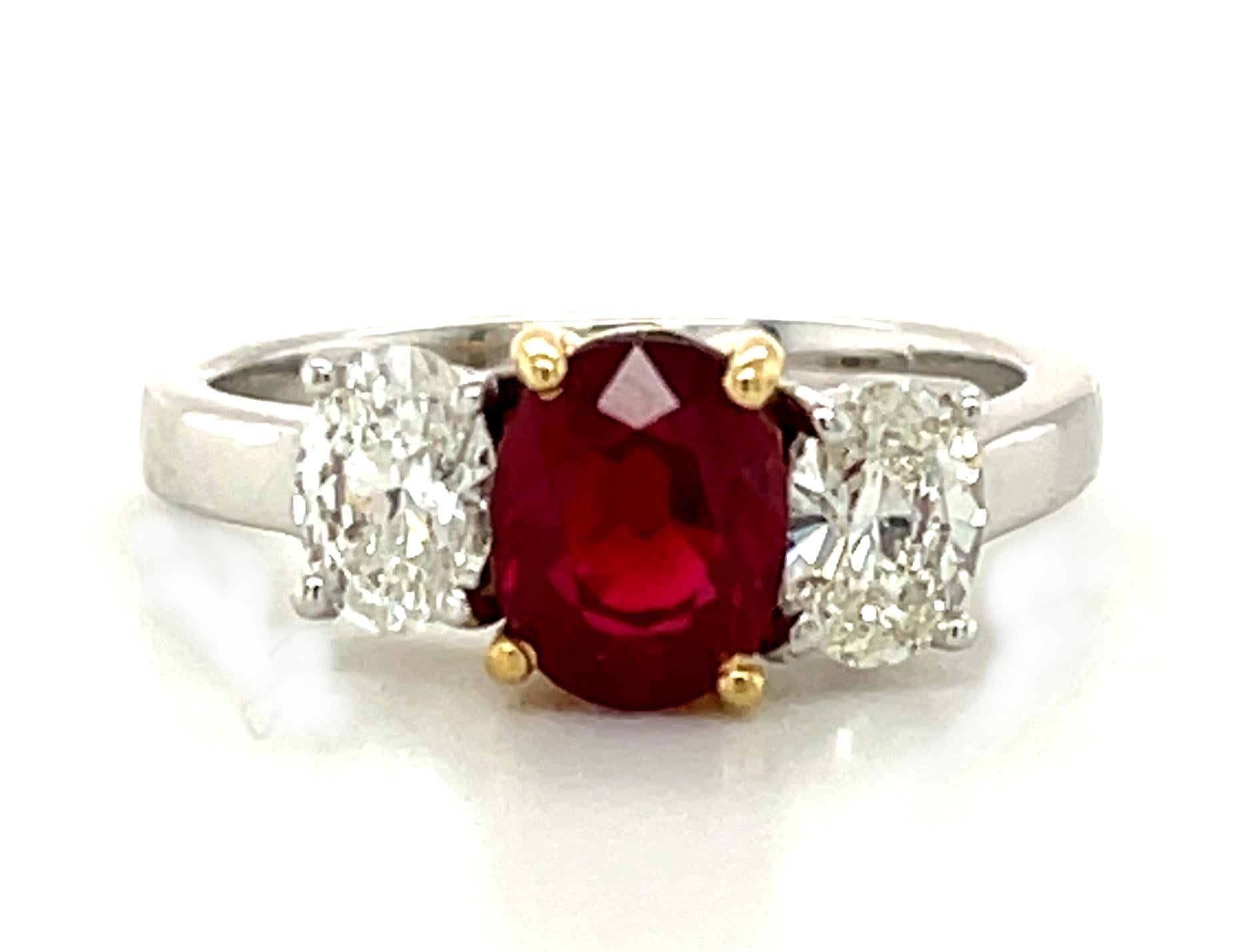 The color of passion! A gorgeous, intense red, oval Burmese ruby is featured in this classic 3-stone ring. The center stone is set in yellow gold and flanked by a matched pair of fine oval brilliant cut diamonds set in 18k white gold. Handmade by