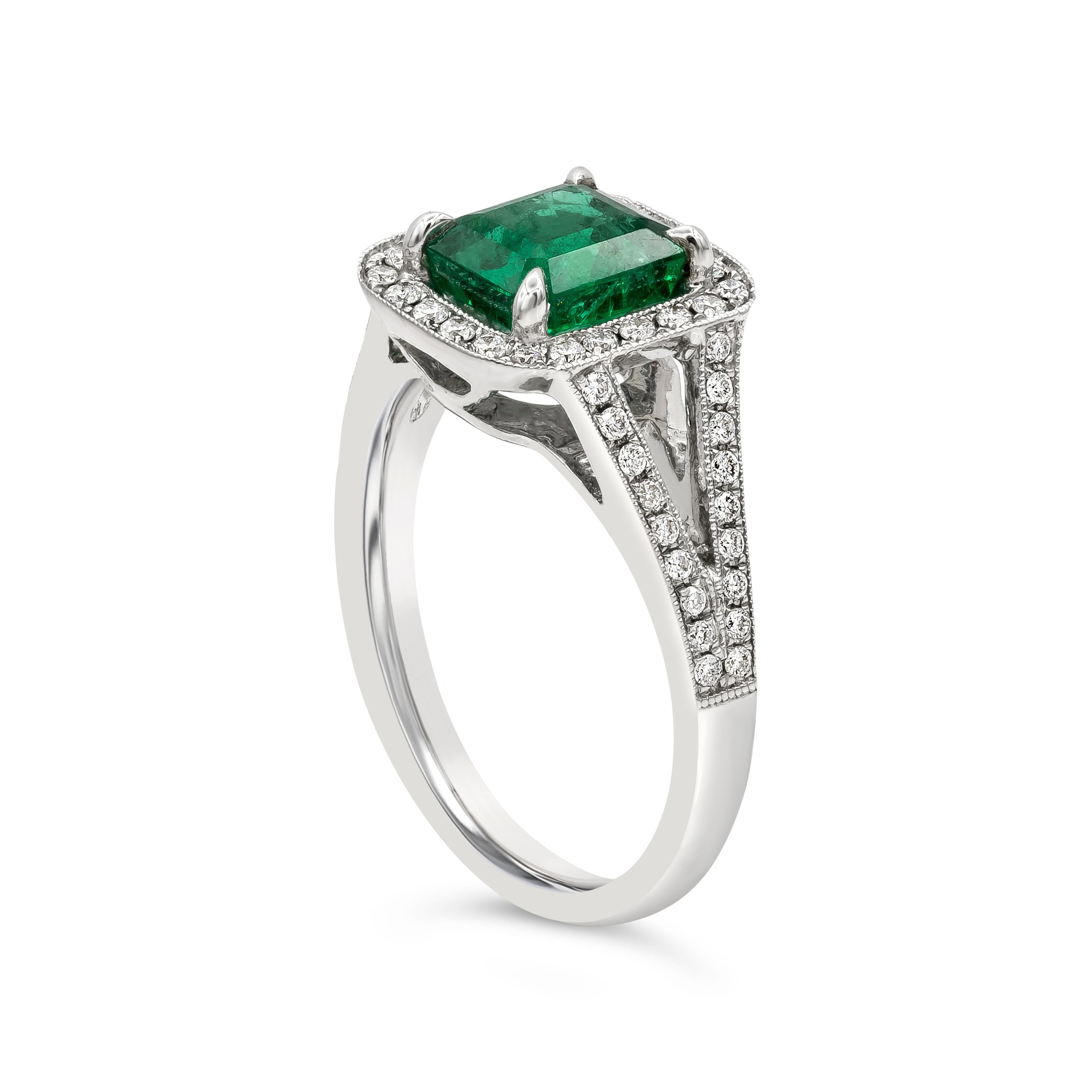 A beautiful engagement ring, featuring a 1.68 carats emerald cut green emerald at the center. Surrounded by a single row of round brilliant cut diamonds set in an antique style split-shank made of 18K white gold. Accent diamonds weigh 0.40 carat