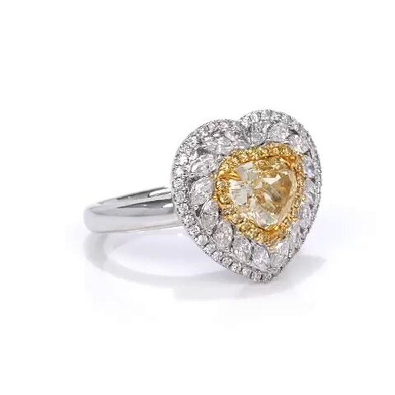 This exquisite handcrafted engagement ring features an 18K white gold band, elegantly showcasing a captivating 1.68 carat heart shaped Fancy Yellow diamond at its center. Encircled by a triple halo of 0.21 carats of Fancy Yellow round diamonds, 0.25