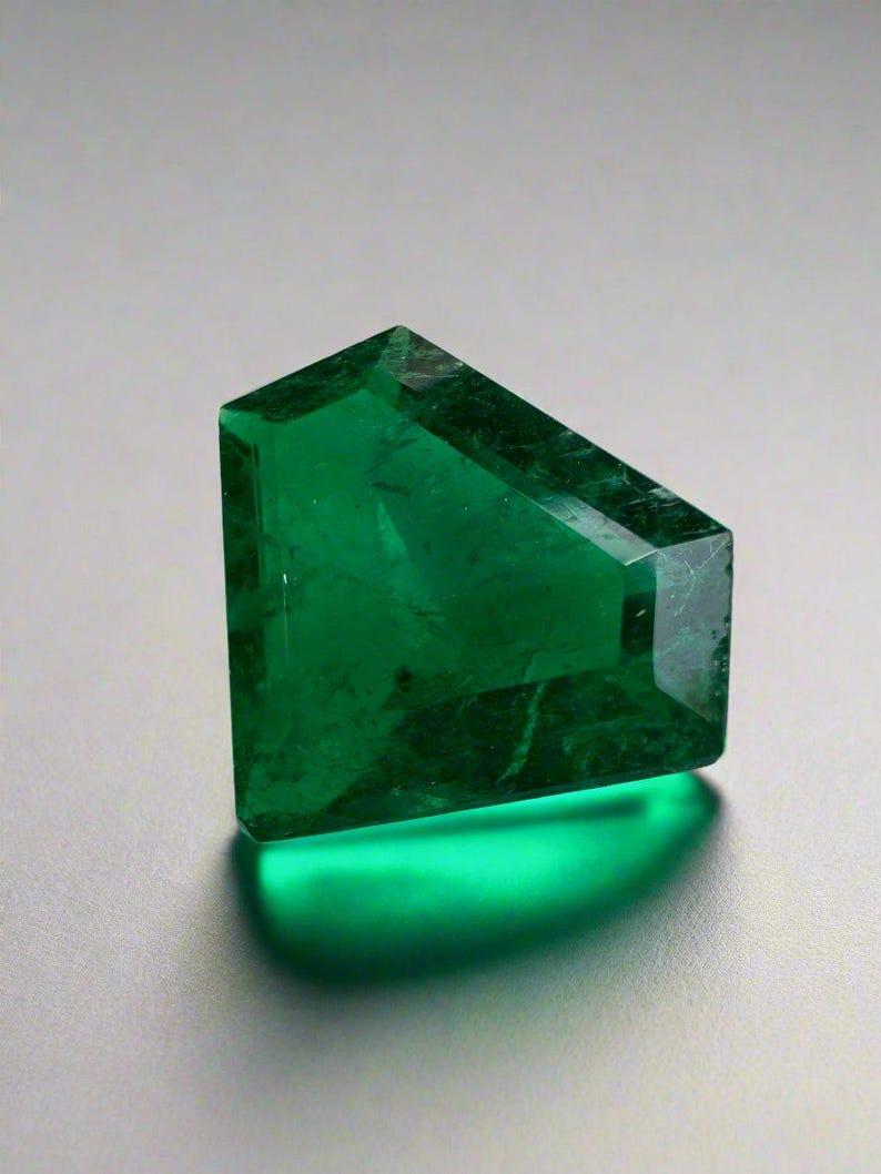 Stone: Emerald
Total Weight: 1.68 Carat
Shape: Shield Cut
Clarity: Transparent
Luster: Very Good
Color: Deep Muzo Green
Measurements: 8.89mm x 11.38mm x 3.47mm
Geographic Origin: Colombia
Treatment: Natural, Oiling

Comments: Due to their growth