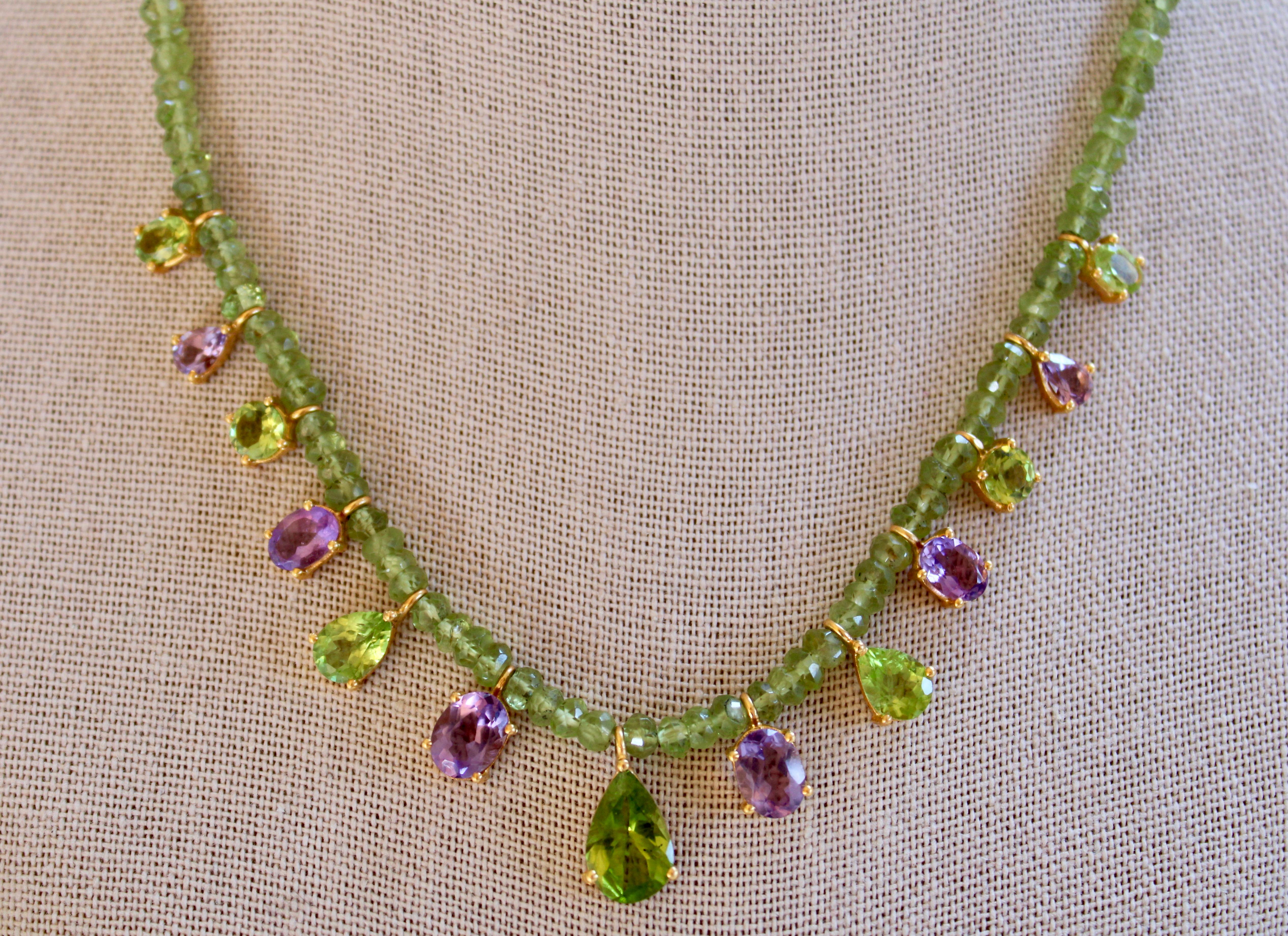 19.75 Ct of green Peridot & purple Amethyst adorn this beautiful peridot beaded necklace. This necklace is comprised of 7 green Peridot gemstones including 2 ovals, 2 rounds, and 3 pears, with the center peridot pear stone at almost 4 carats. 
There