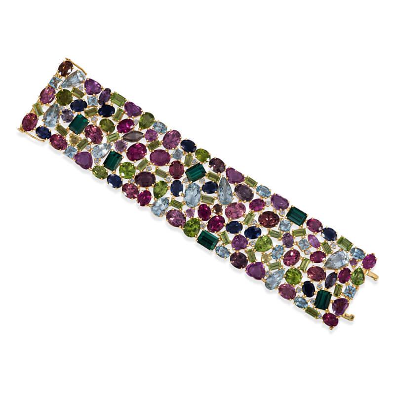 Exceptionally designed wide bracelet in 18KT yellow gold featuring a mixed assortment of colored tourmaline gemstones (in pale and dark green, varying colors of pink, yellow, light and deep blue) in a variety of shapes including heart, pear, oval,