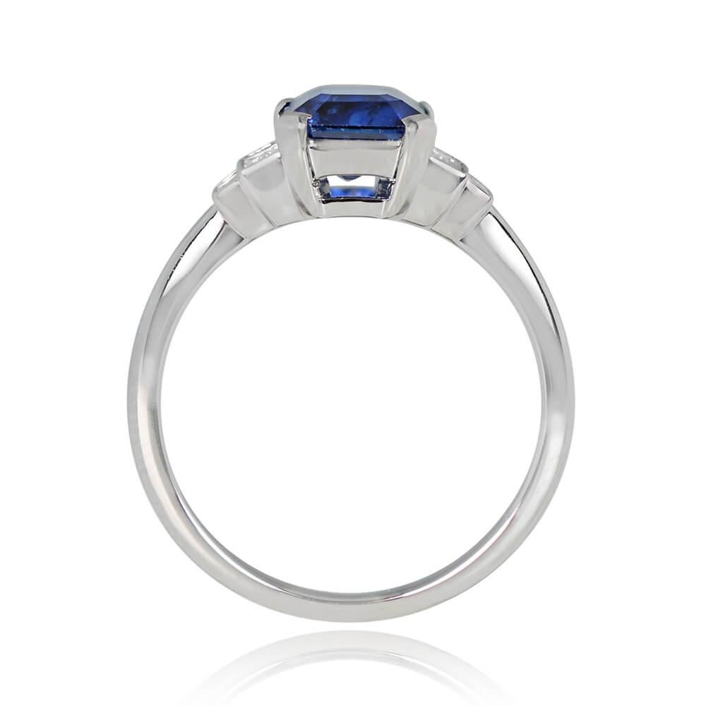 A geometric engagement ring featuring a 1.68-carat emerald-cut natural sapphire, set in prongs and displaying a deep blue color. A graduating design of baguette-cut diamonds sits on either side of the center stone. The total diamond weight is 0.24